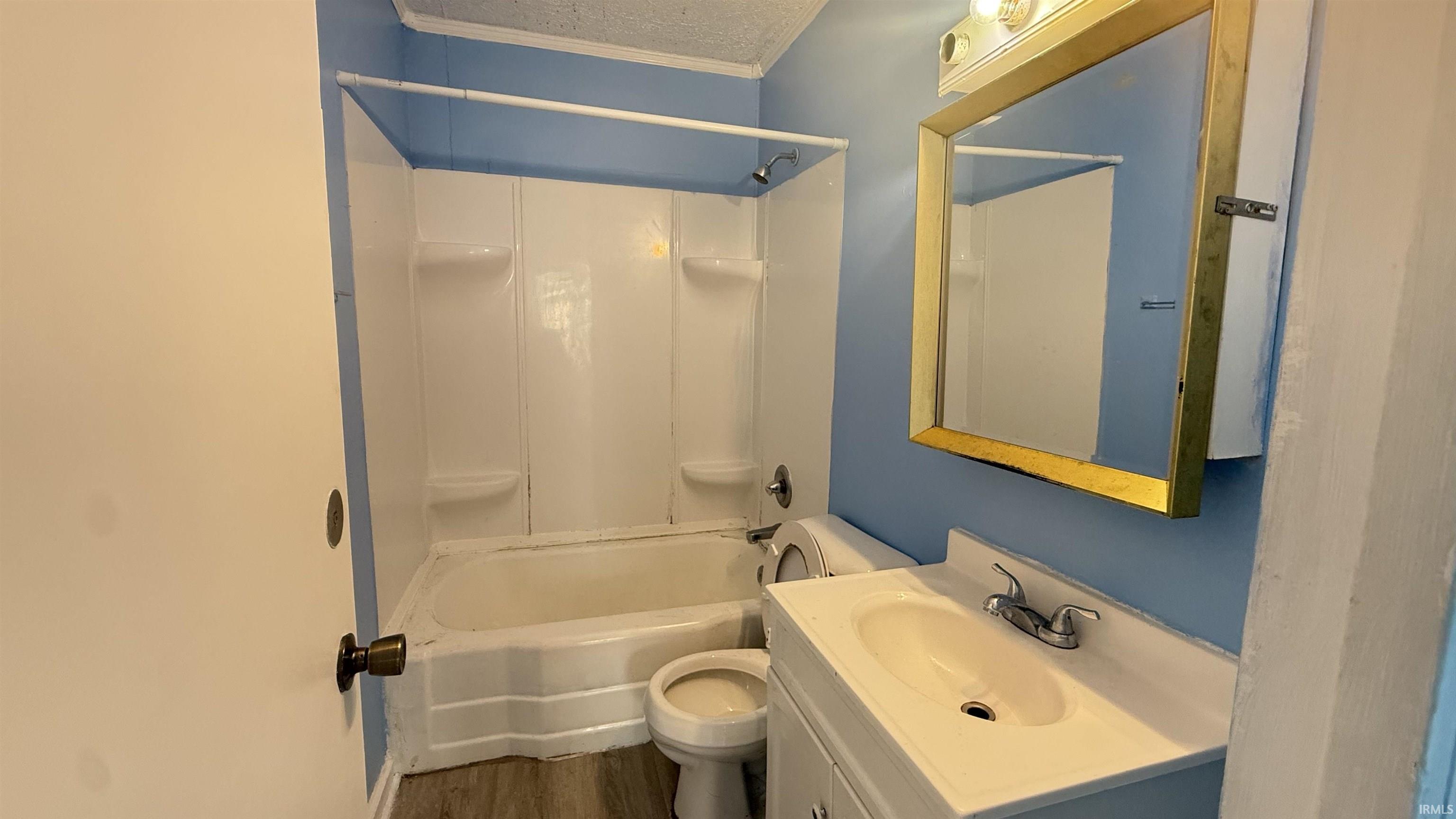 Full bathroom with vanity,  shower combination, dark wood-type flooring, and a textured ceiling