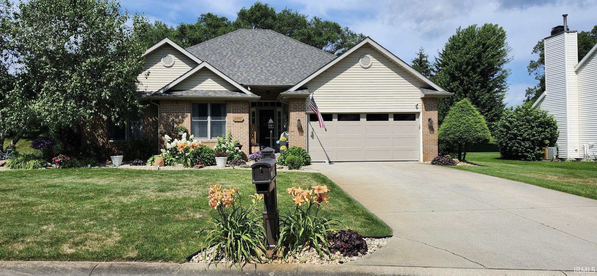 View of front of house with brick siding, a front yard, driveway, an attached garage, and a shingled roof