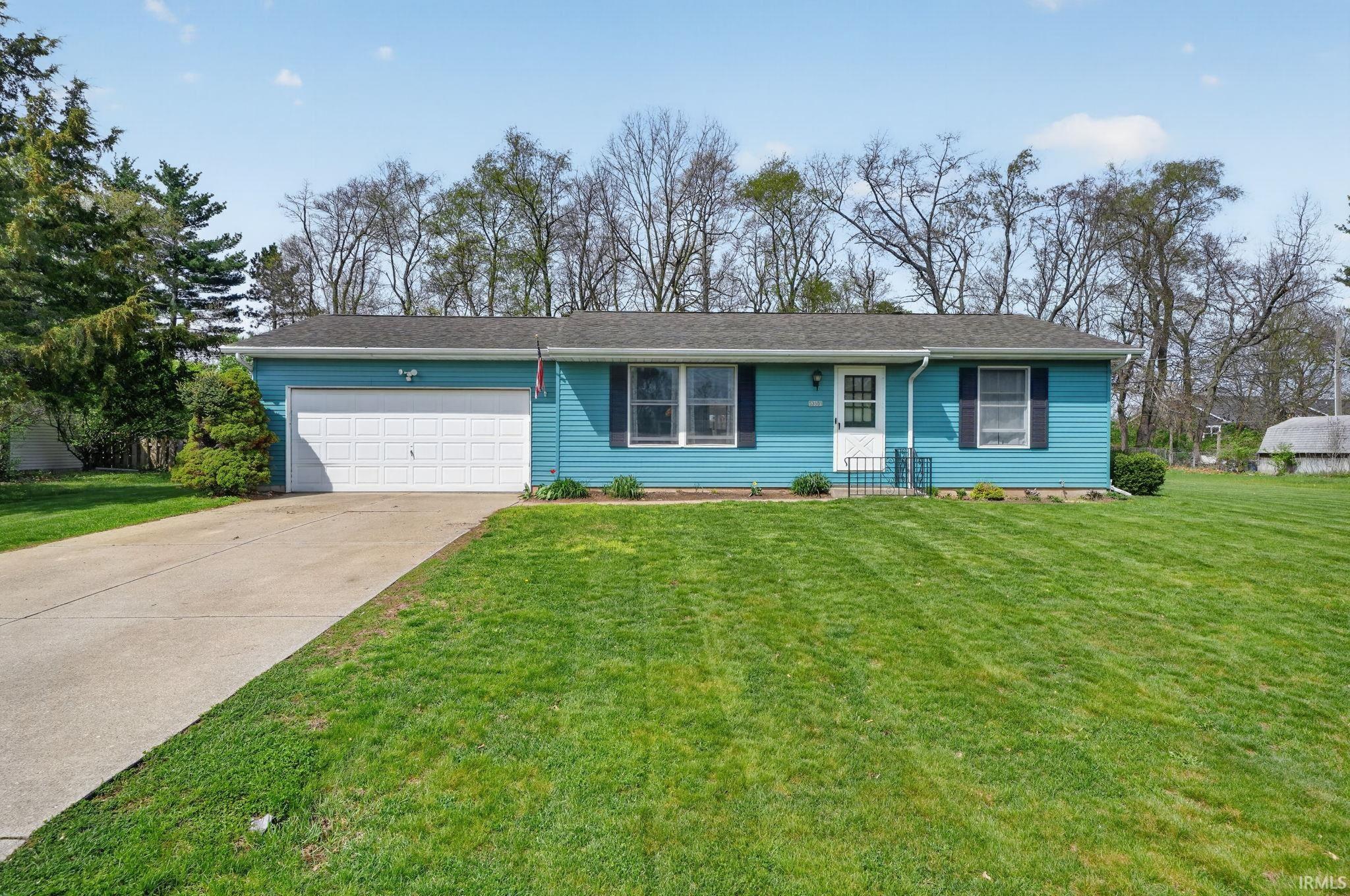 Ranch-style house with a front yard, a garage, and concrete driveway