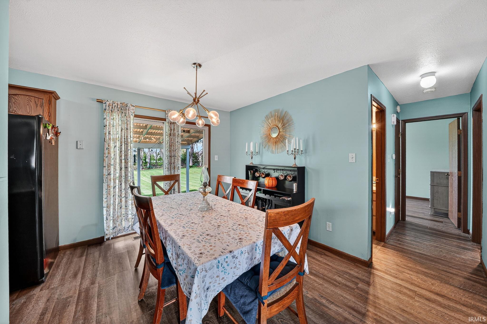Dining area featuring dark wood-style flooring and a chandelier