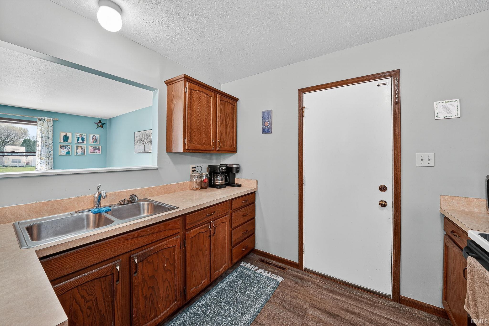 Kitchen with light countertops, dark wood finished floors, a textured ceiling, and wood finish cabinetry