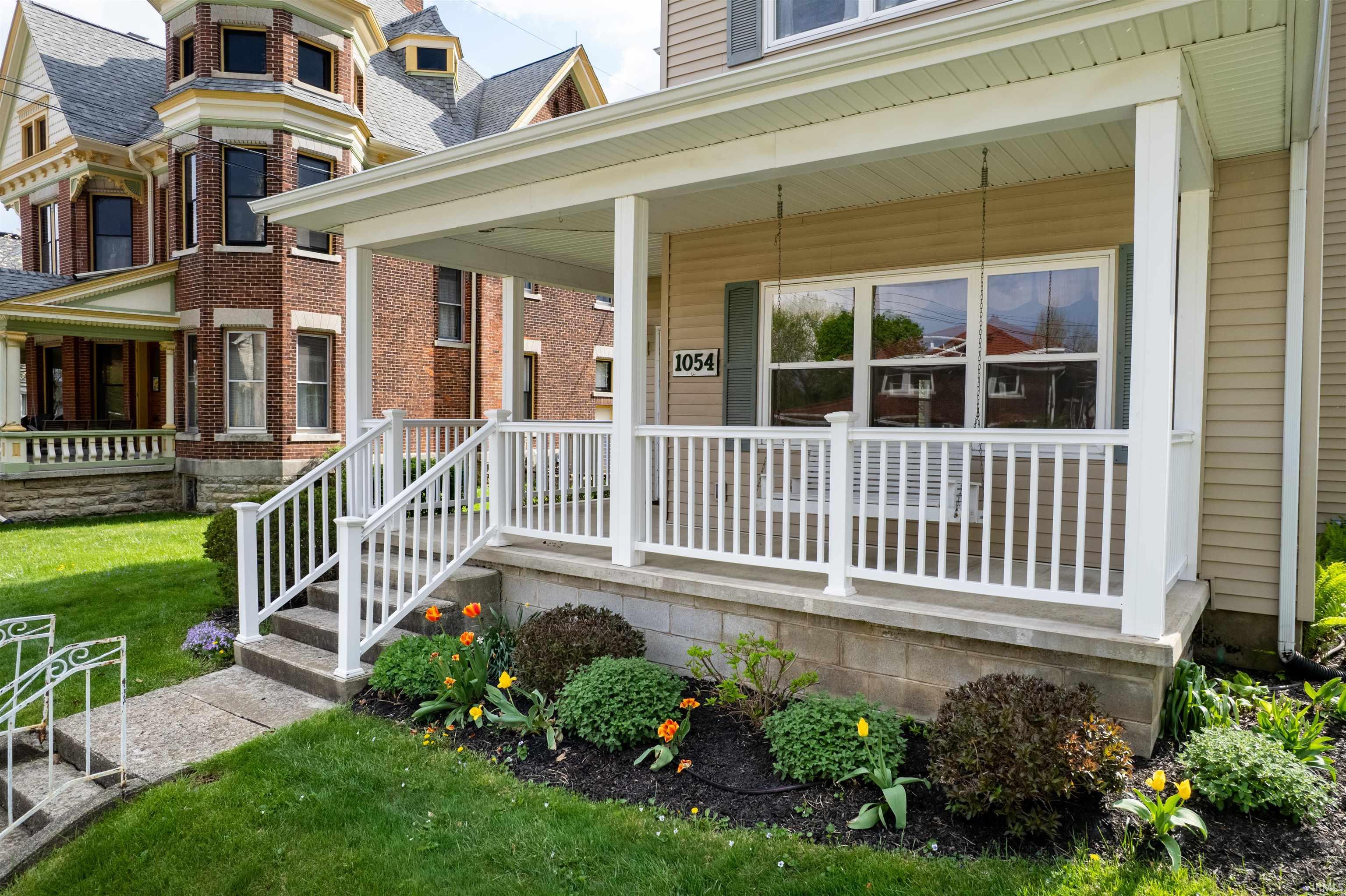 Property entrance featuring a porch, a lawn, and brick siding