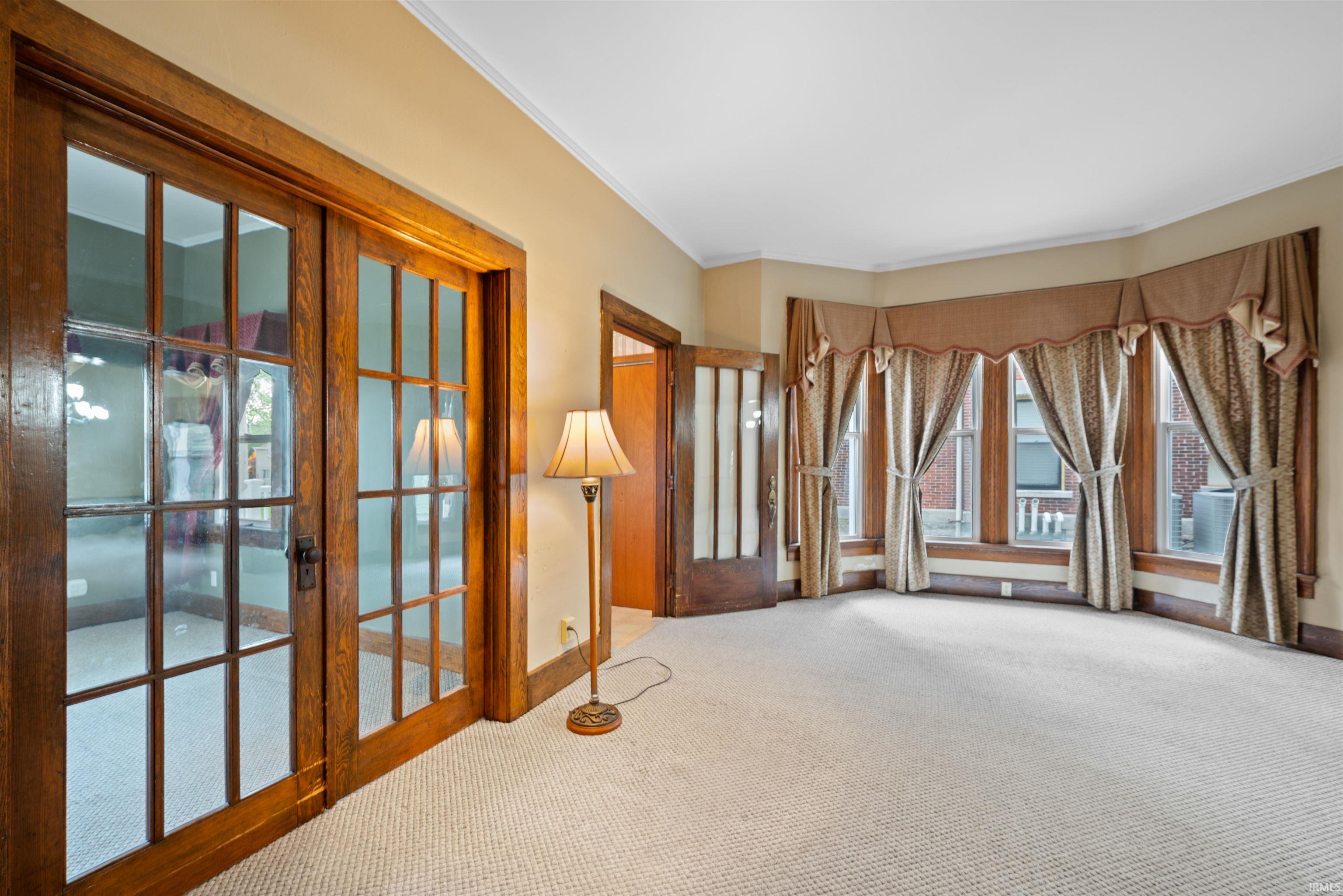 Spare room featuring light carpet, ornamental molding, and french doors