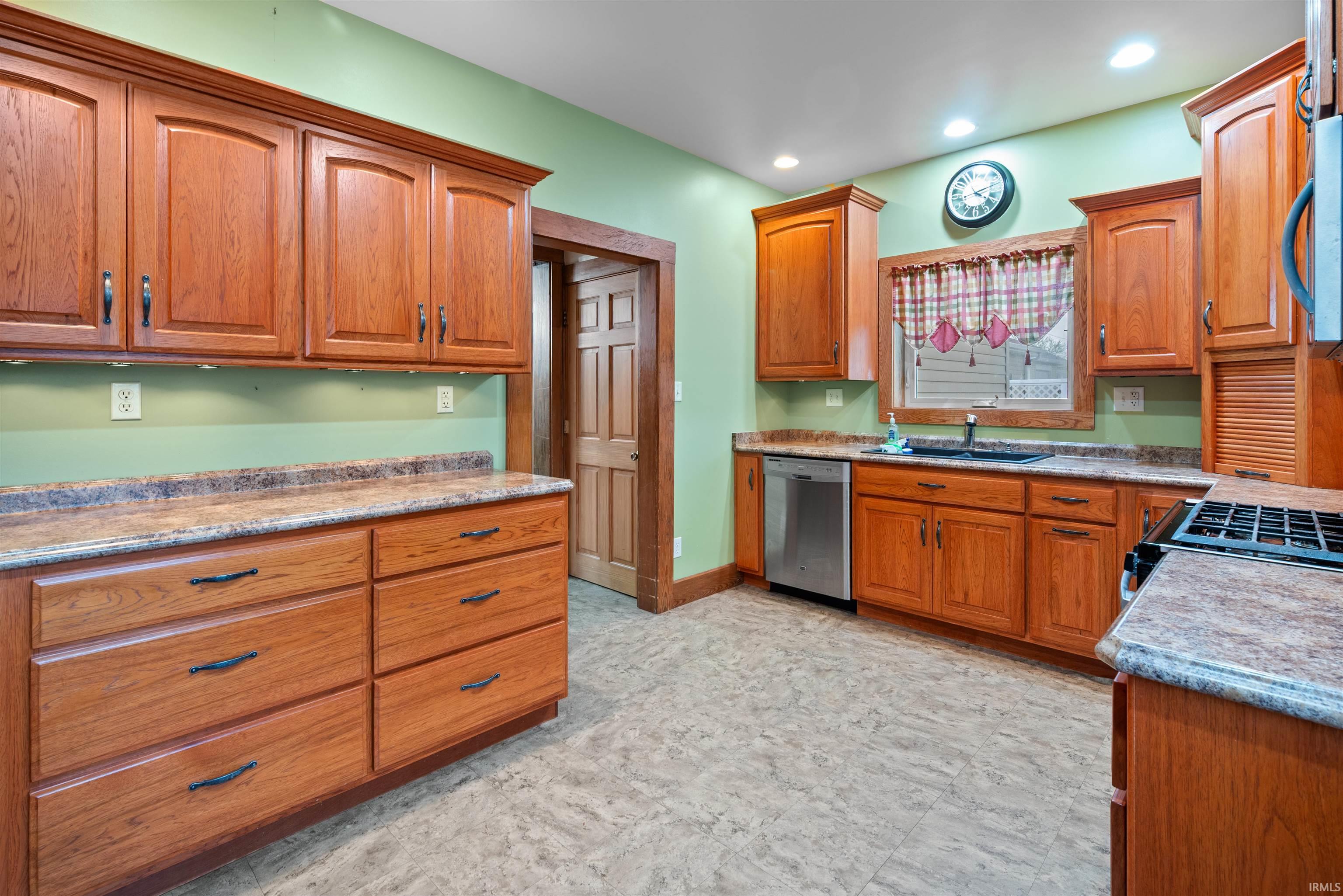 Kitchen with wood finish cabinets, stainless steel appliances, and light floors