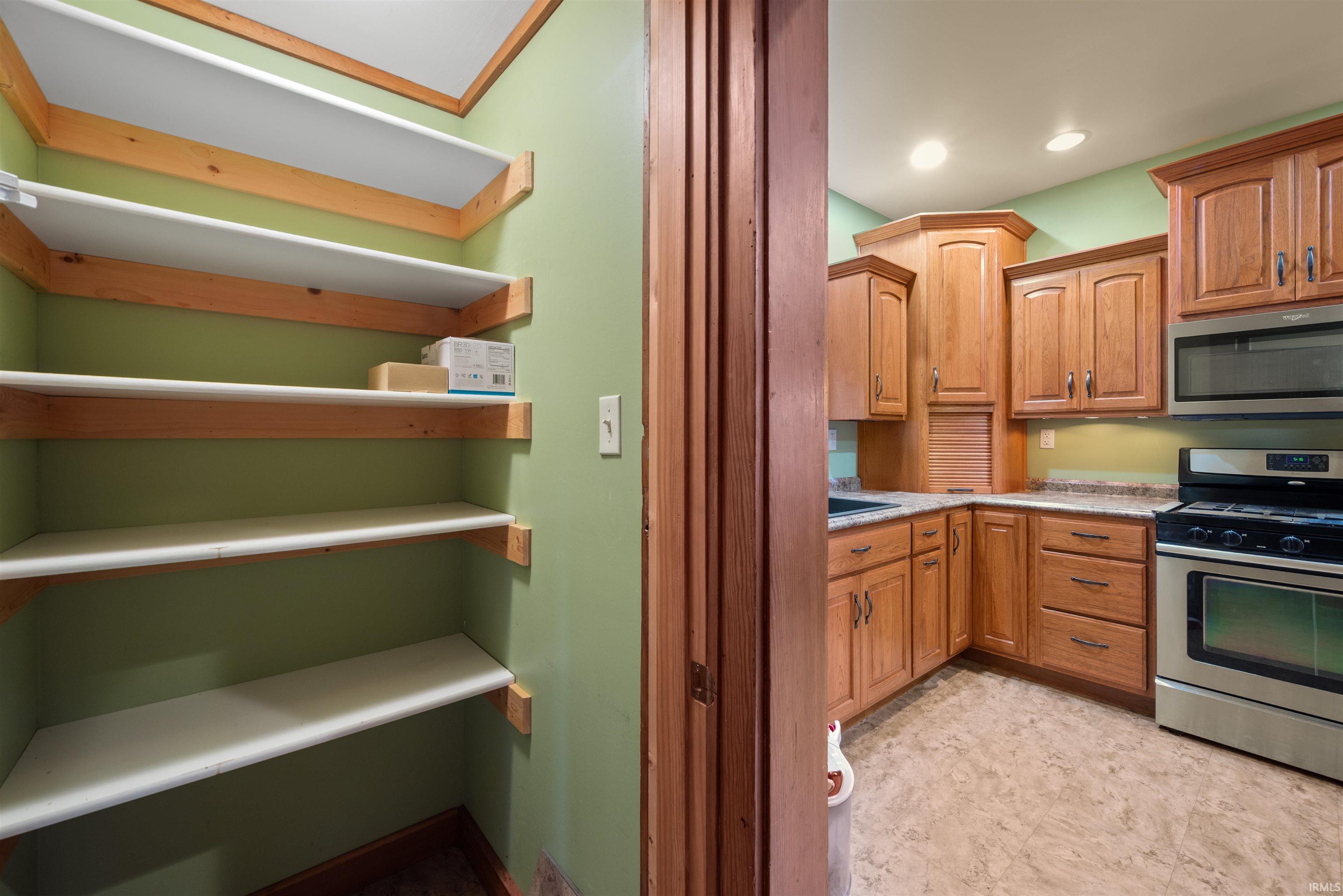 Kitchen with stainless steel appliances, wood finish cabinetry, and light stone counters
