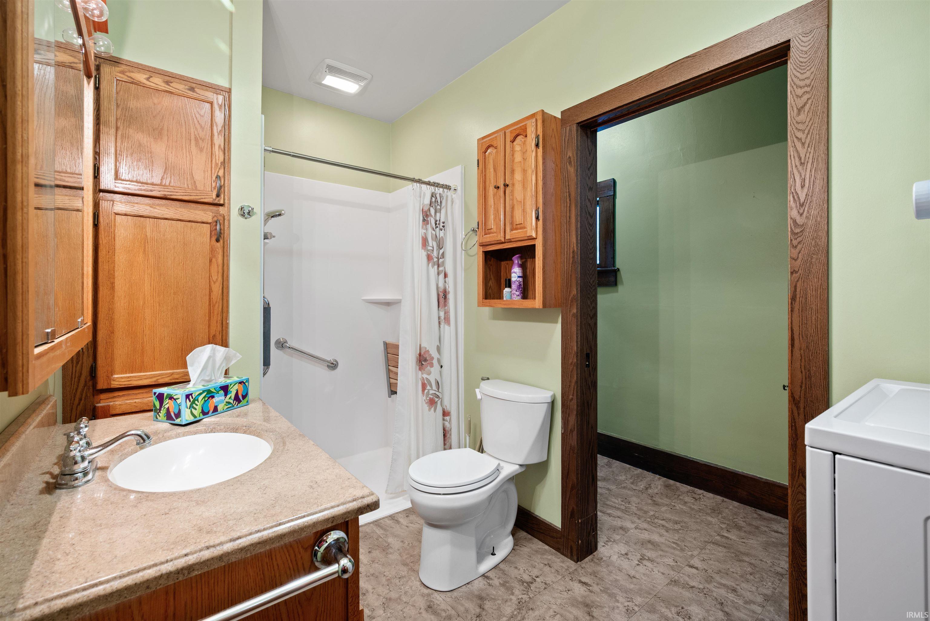 Full bathroom with vanity, washer / dryer, and a shower stall