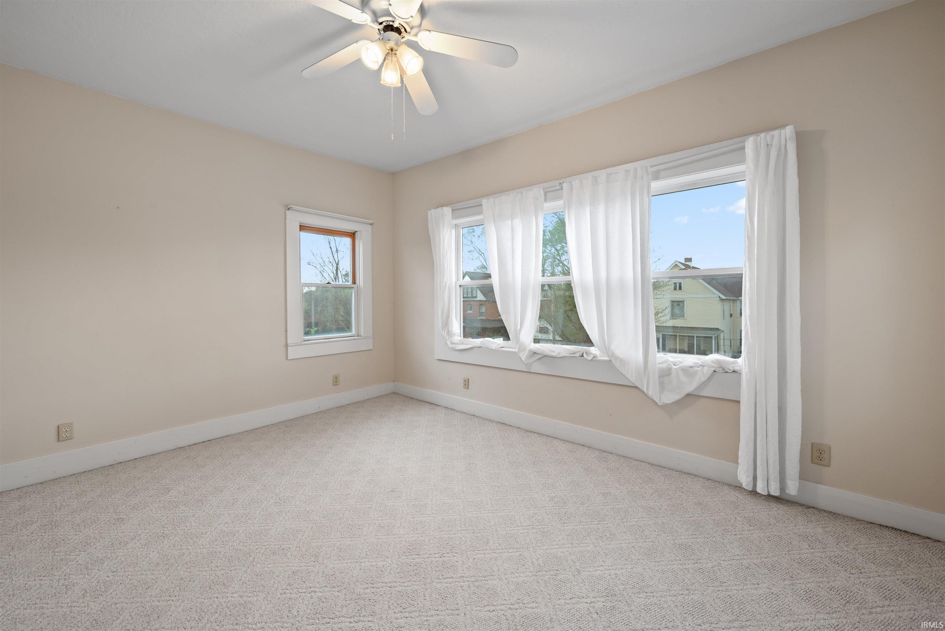 Spare room featuring light carpet and a ceiling fan
