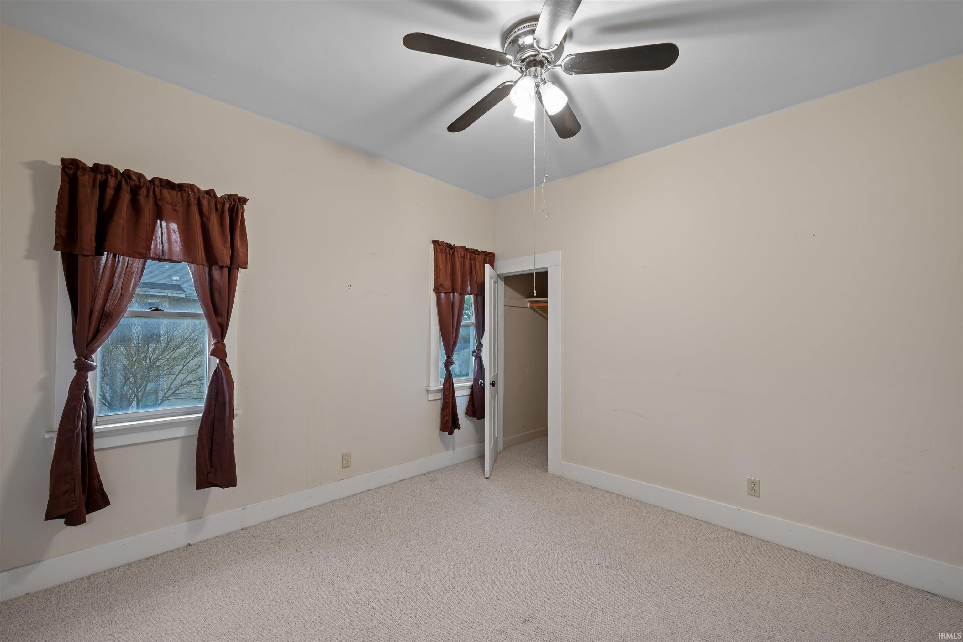 Unfurnished bedroom with light carpet and ceiling fan