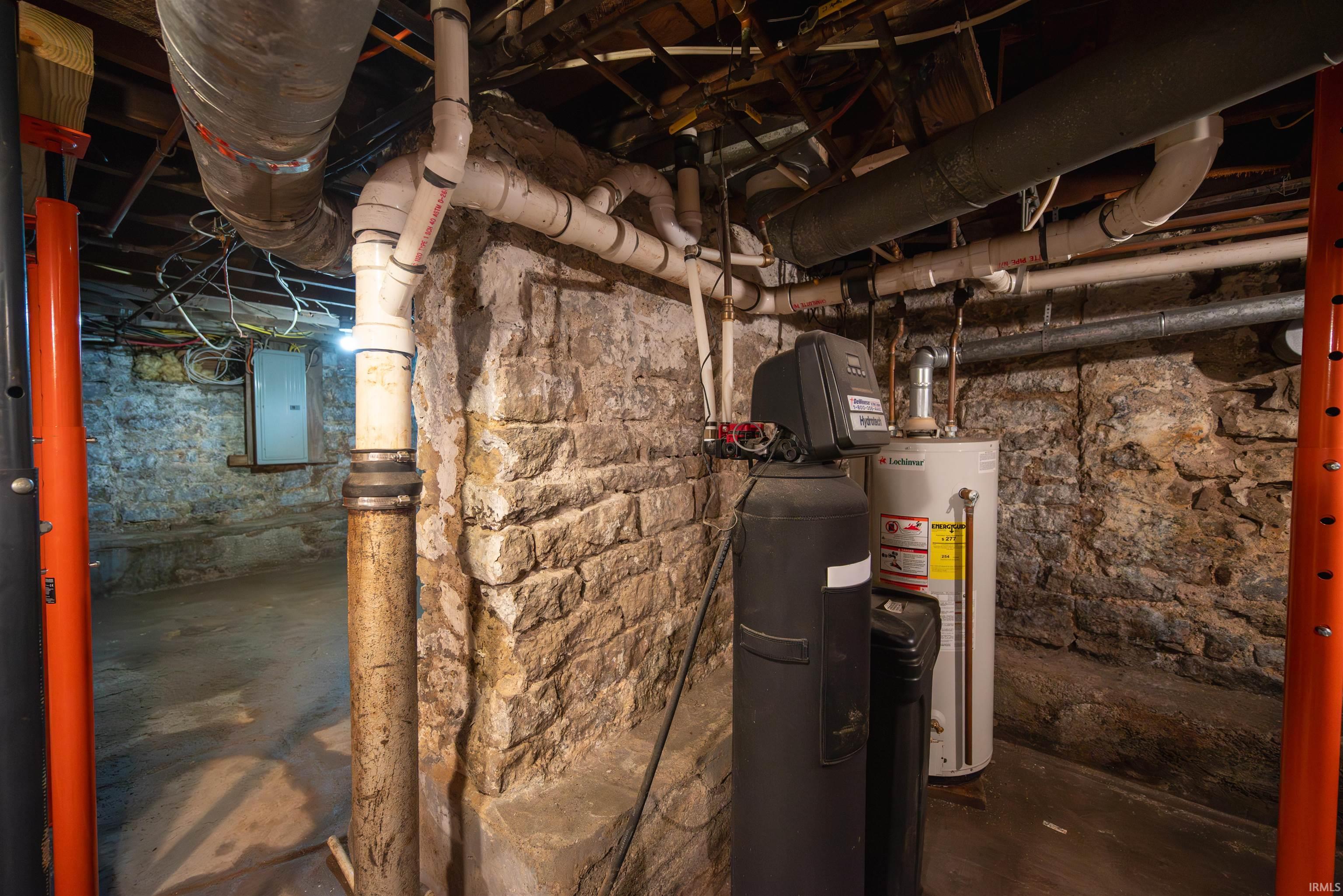 Unfinished below grade area featuring electric panel, water heater, and a water softener