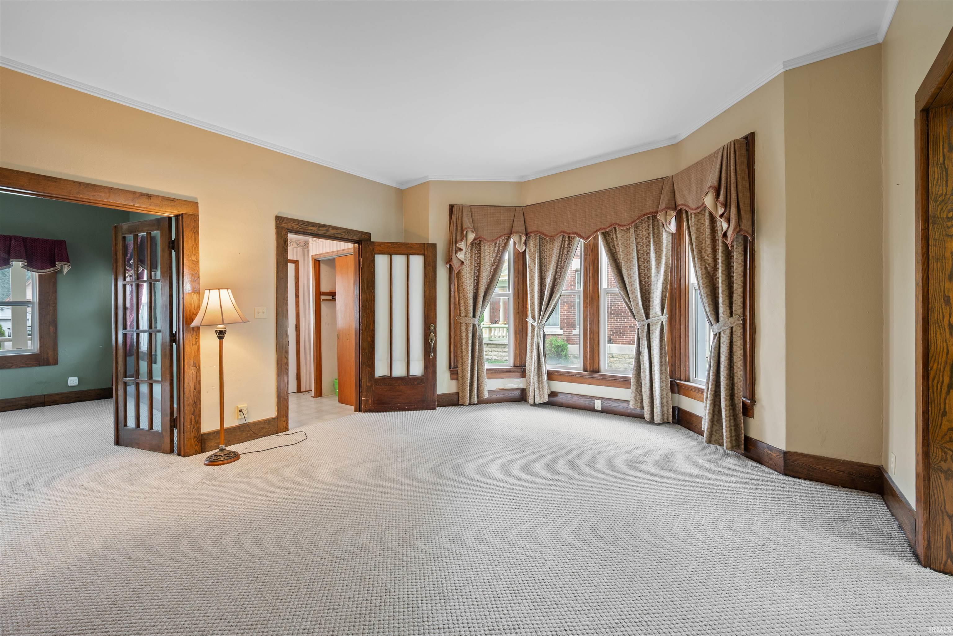 Unfurnished room featuring light colored carpet and crown molding