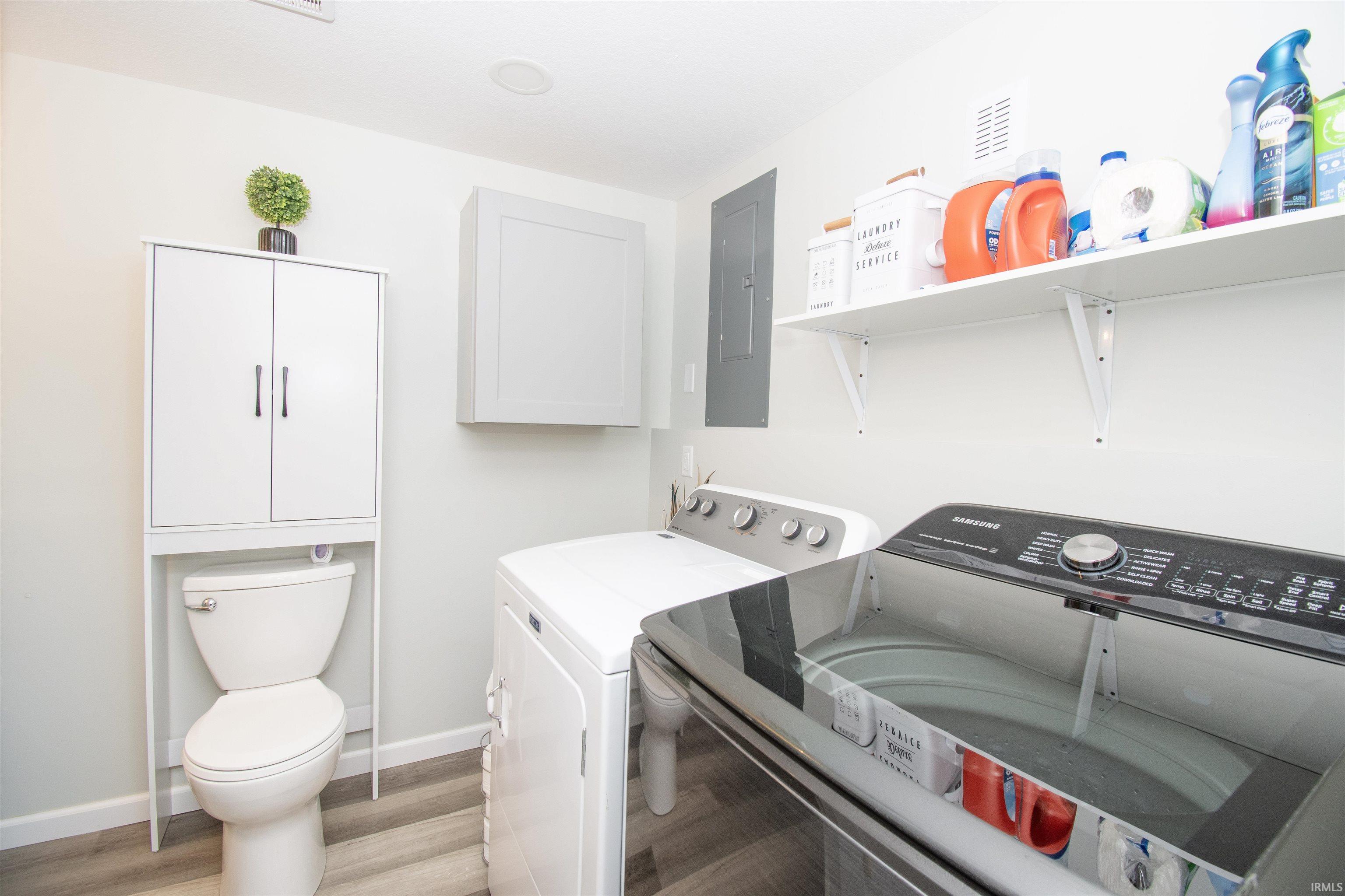 Laundry area with light wood-style flooring, electric panel, and independent washer and dryer