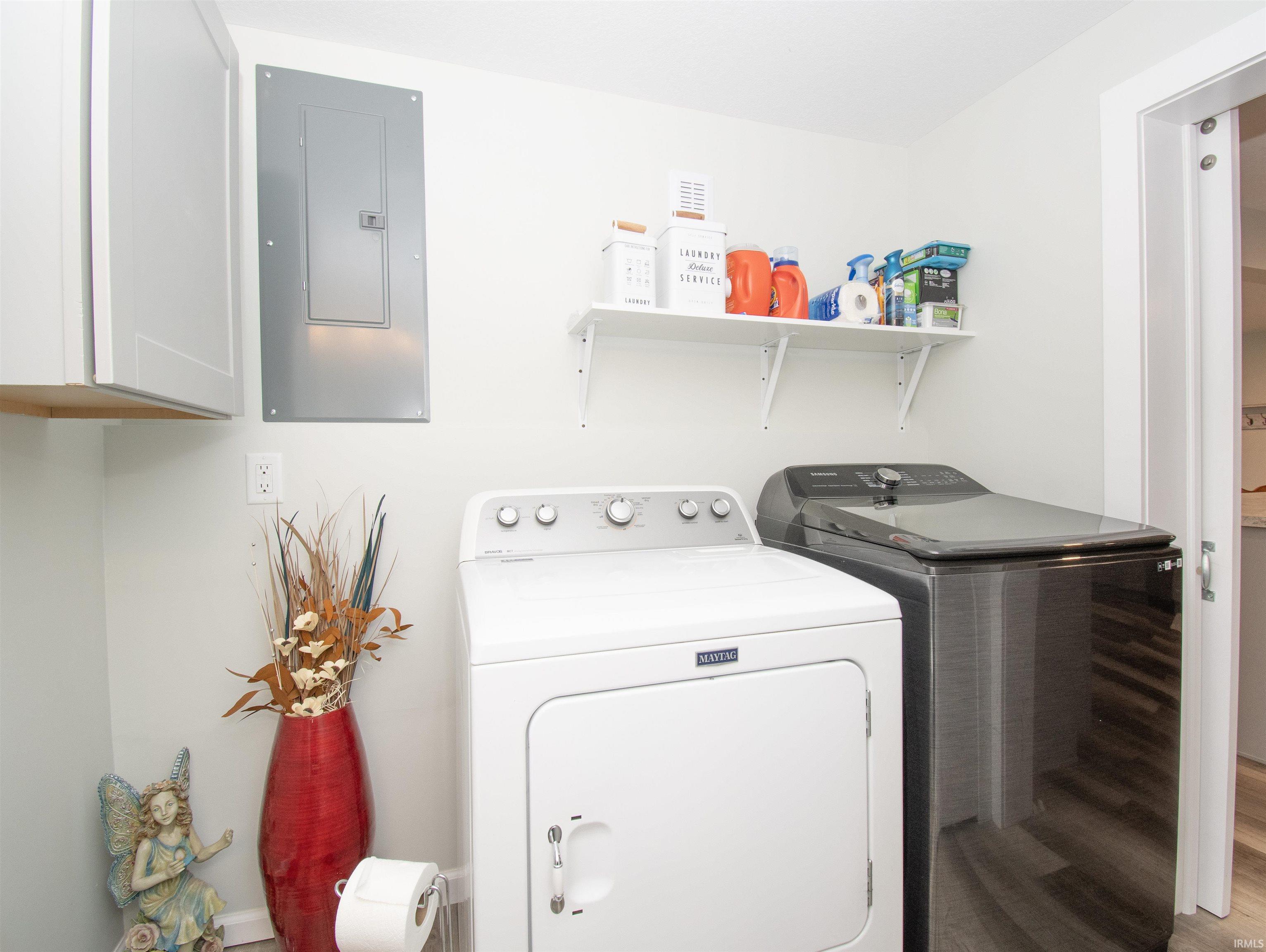 Laundry room featuring electric panel, light wood-type flooring, and washer and dryer