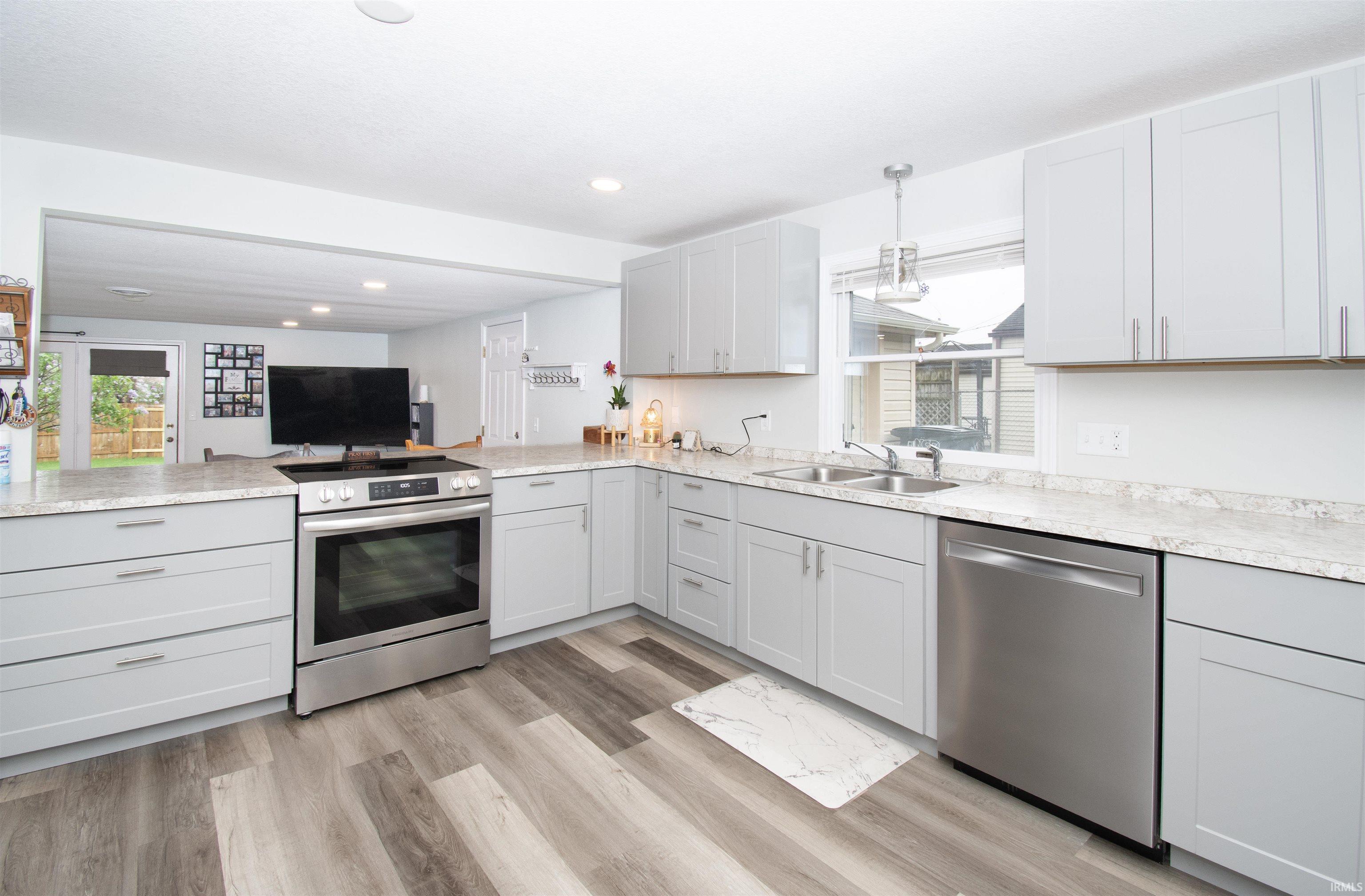 Kitchen with stainless steel appliances, light countertops, a peninsula, and light wood-type flooring