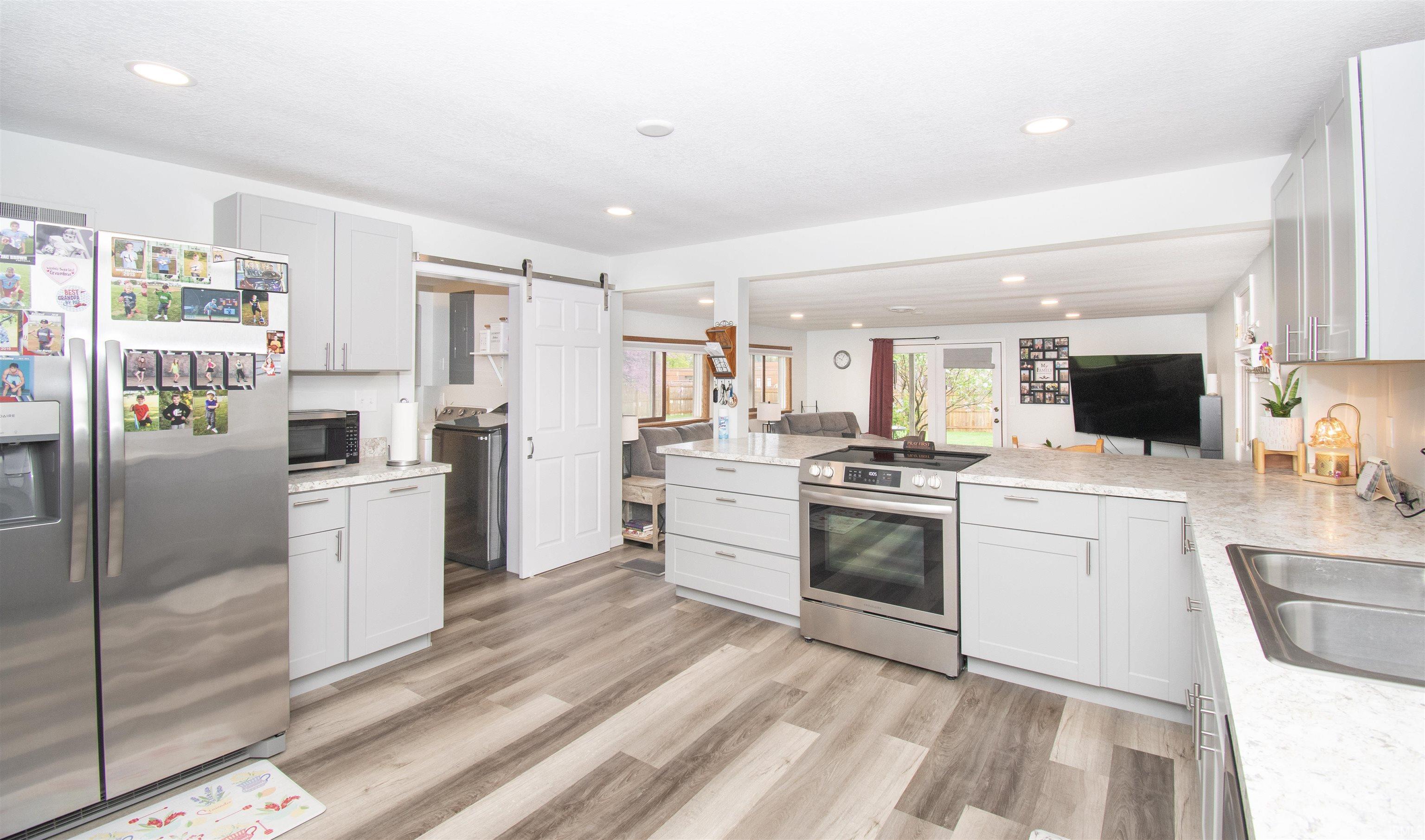 Kitchen with a barn door, stainless steel appliances, a peninsula, light wood-style floors, and open floor plan