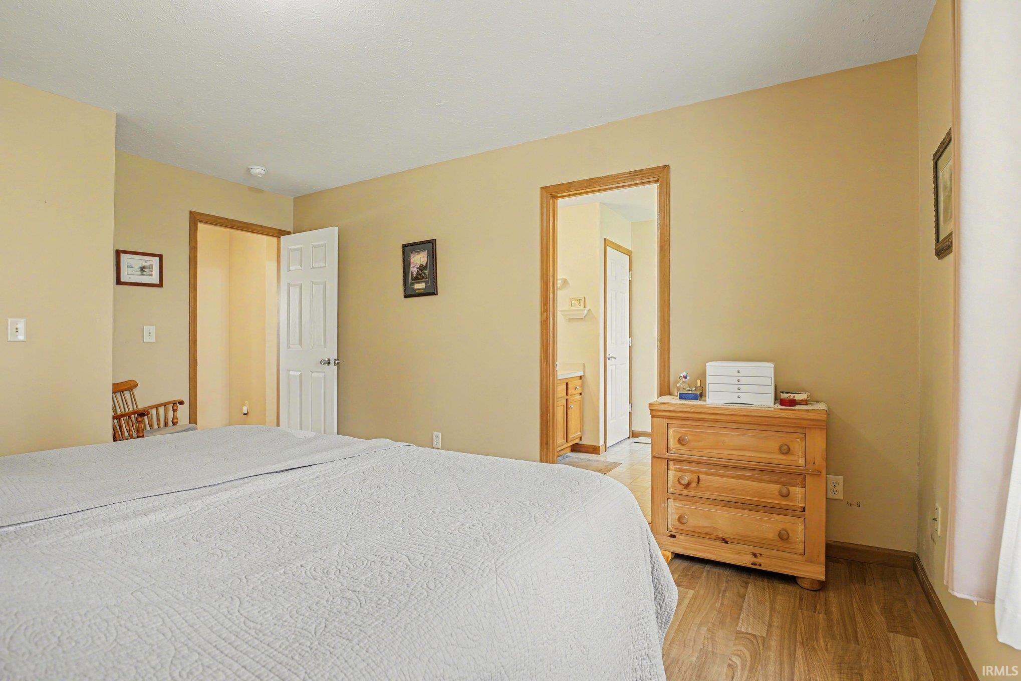 Bedroom with light wood-type flooring and ensuite bath