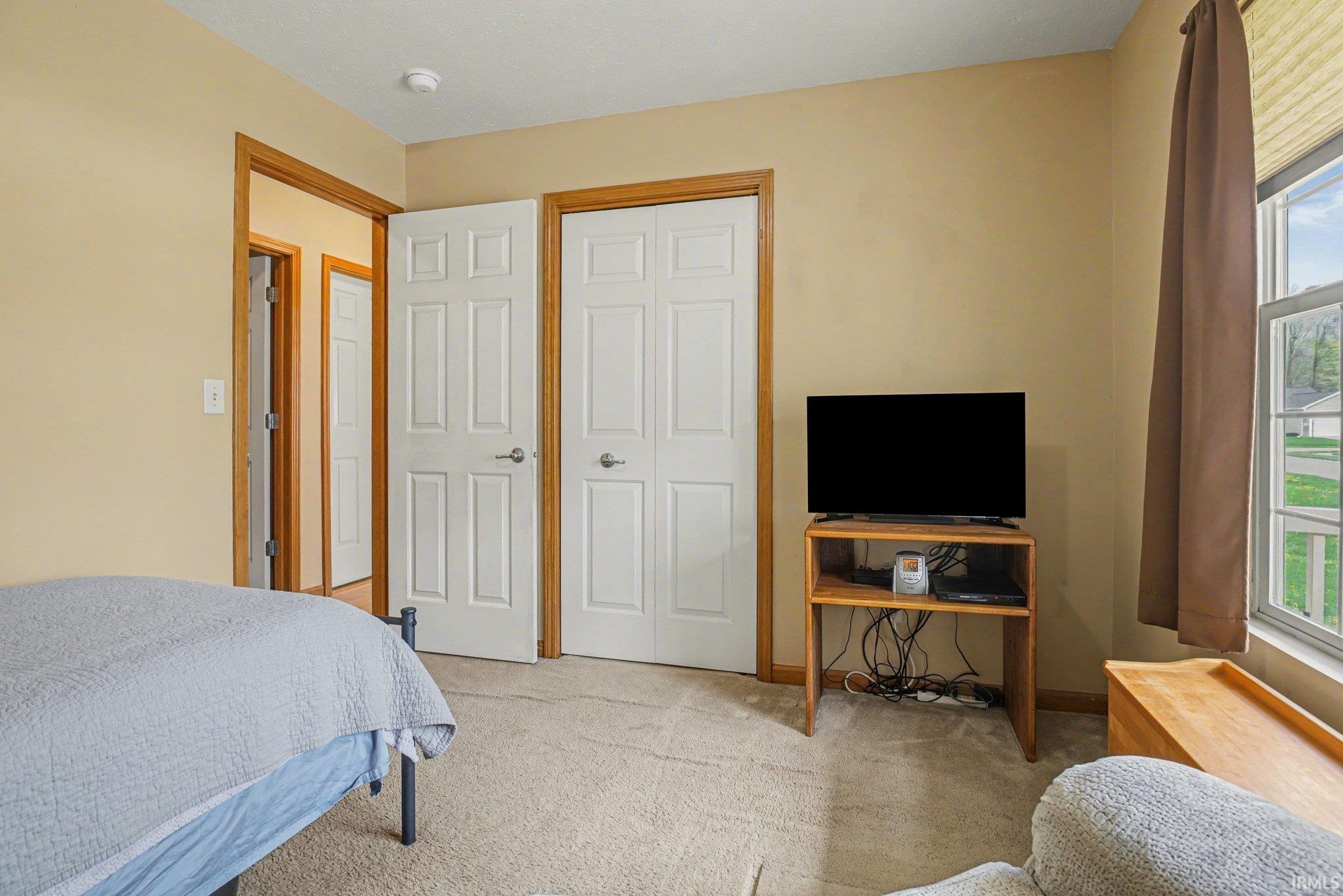 Bedroom with light carpet and a closet
