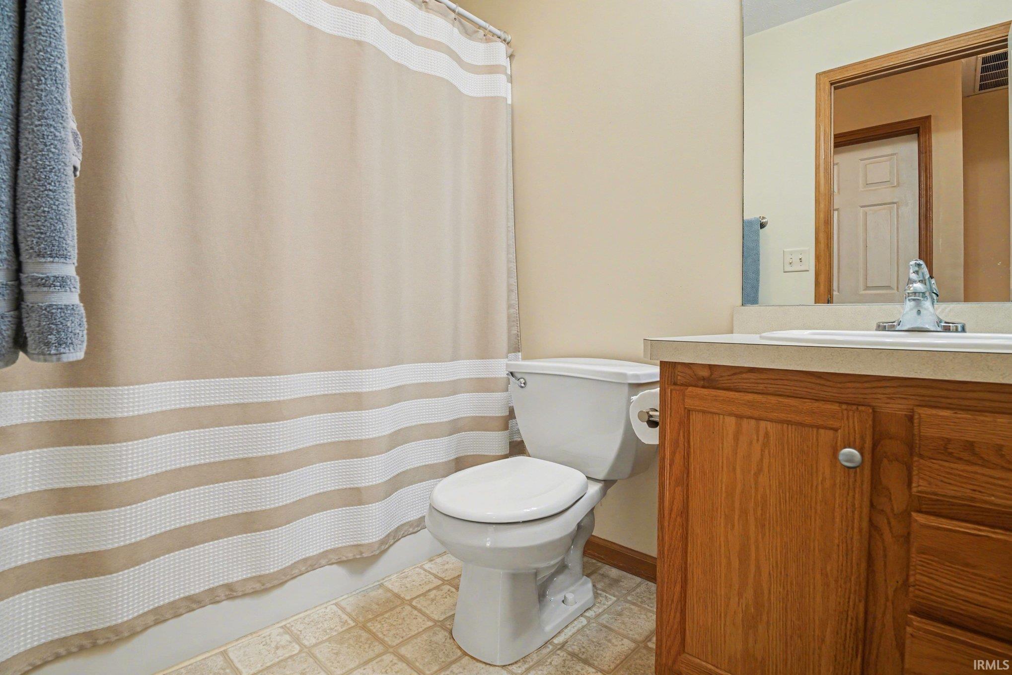 Bathroom with a shower with curtain, vanity, and light flooring
