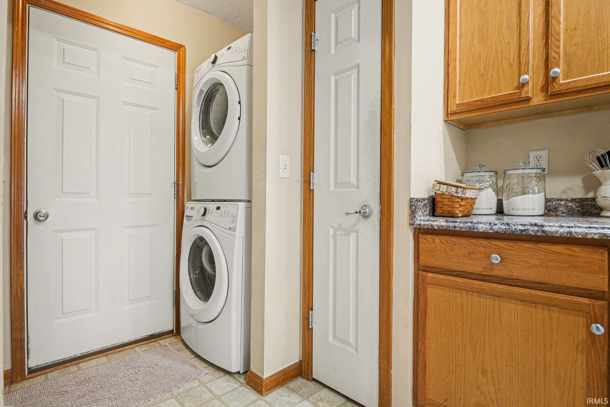 Laundry room with light flooring and stacked washer and dryer