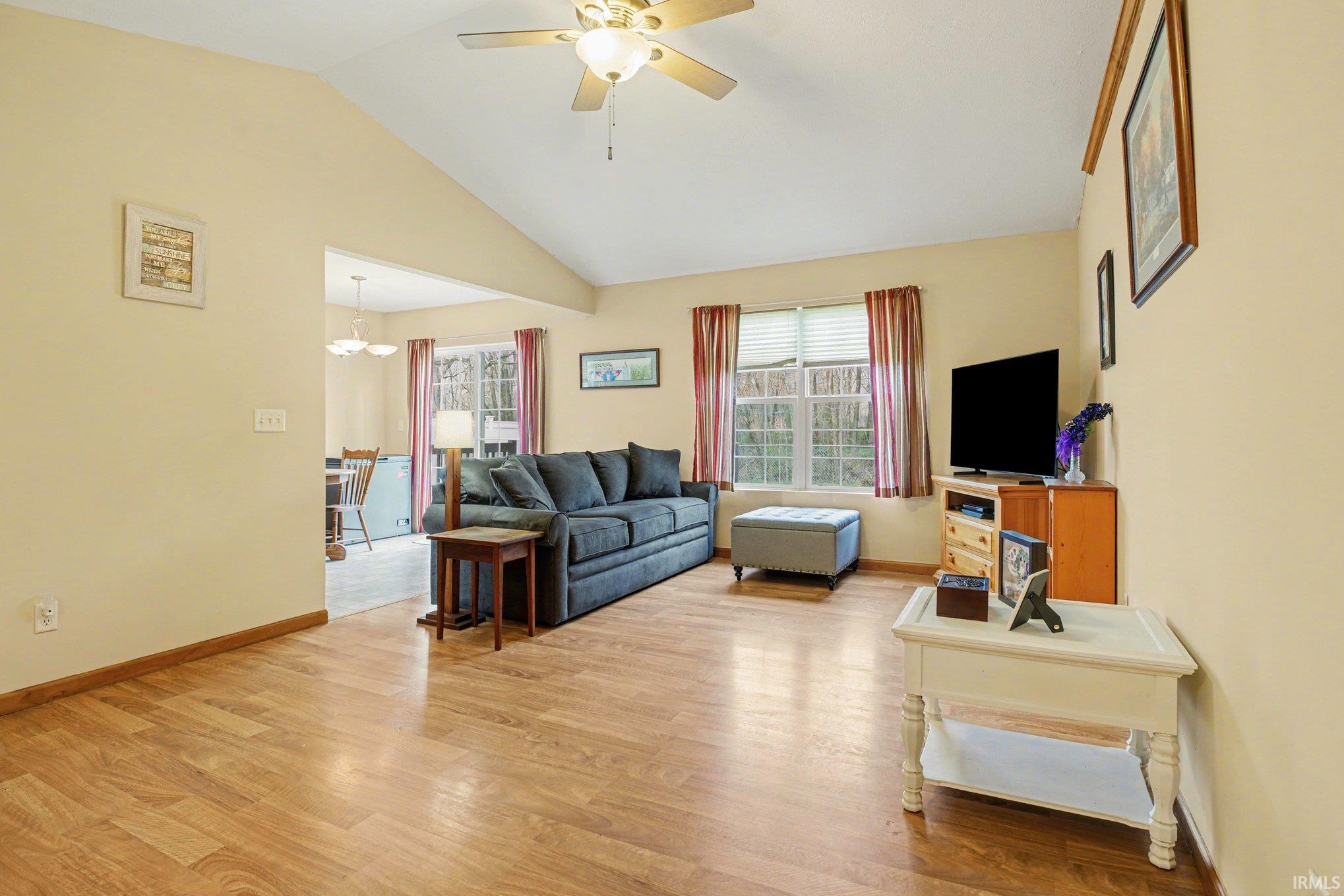 Living area featuring a ceiling fan, light wood-type flooring, lofted ceiling, and healthy amount of natural light