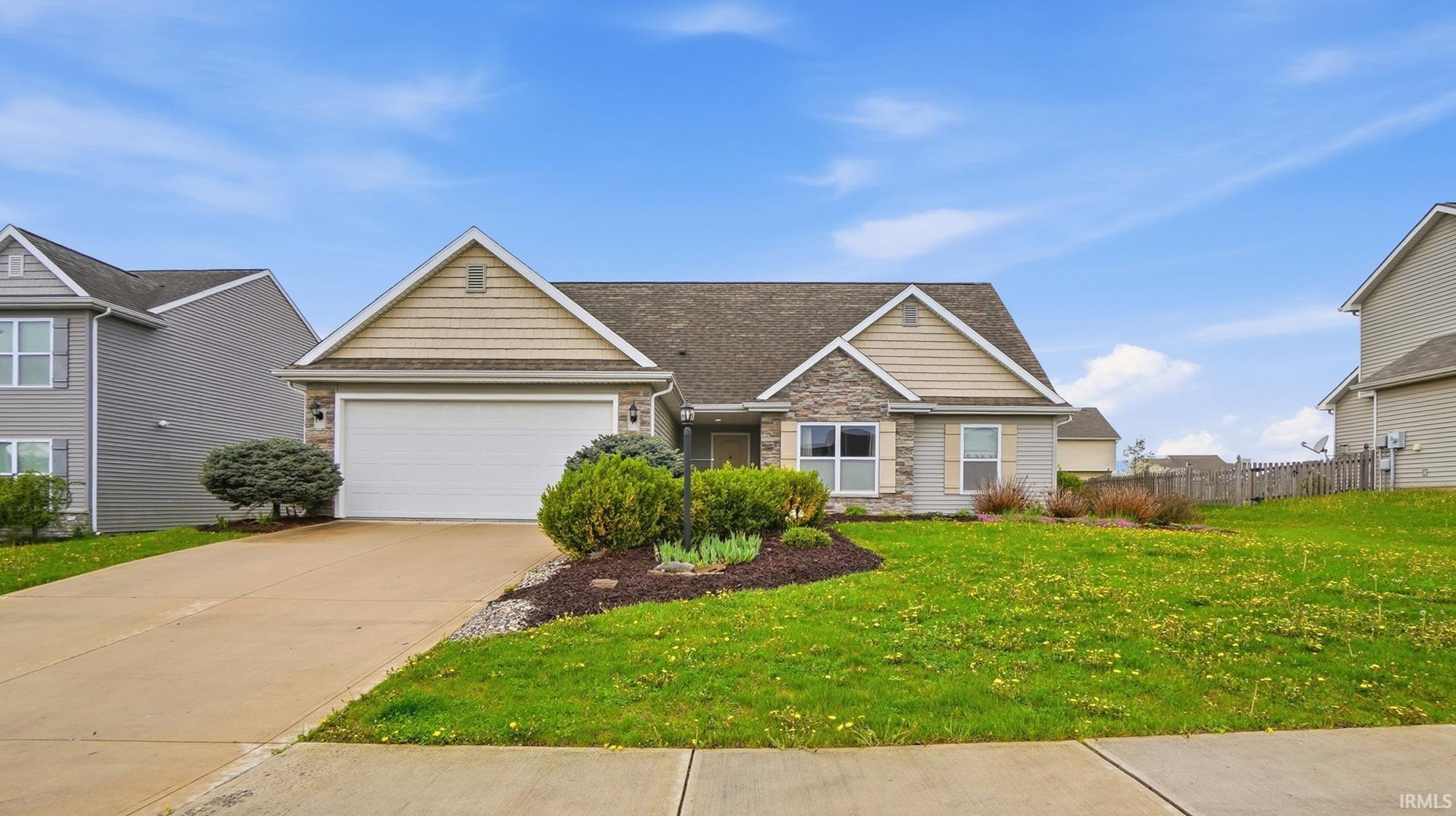 View of front of home with stone siding, an attached garage, concrete driveway, and a shingled roof
