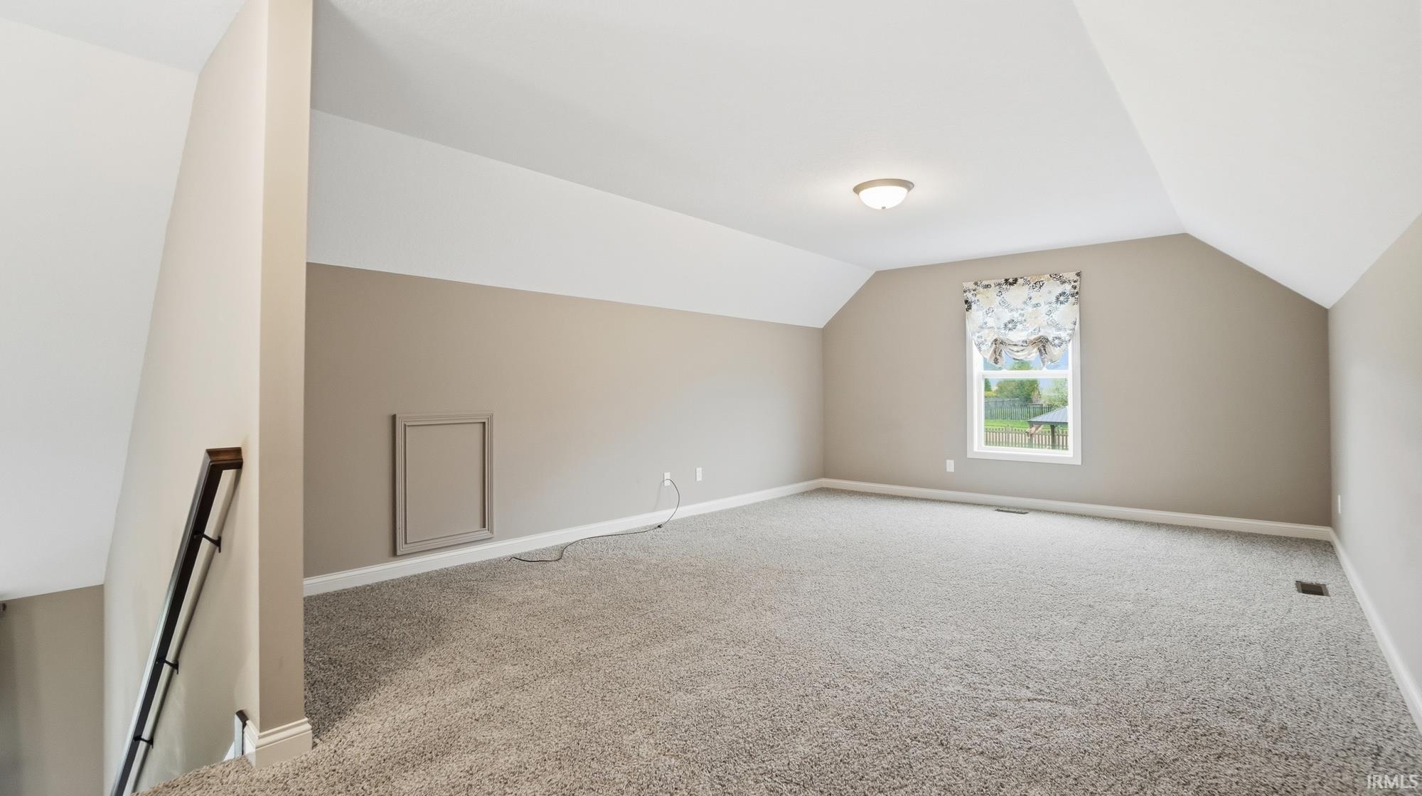 Bonus room with light carpet and baseboards
