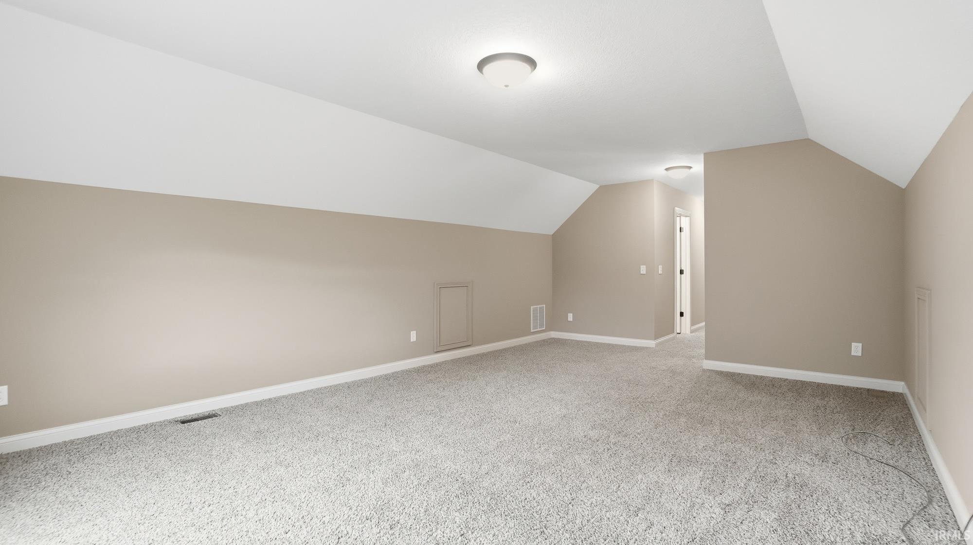 Additional living space with light carpet and baseboards