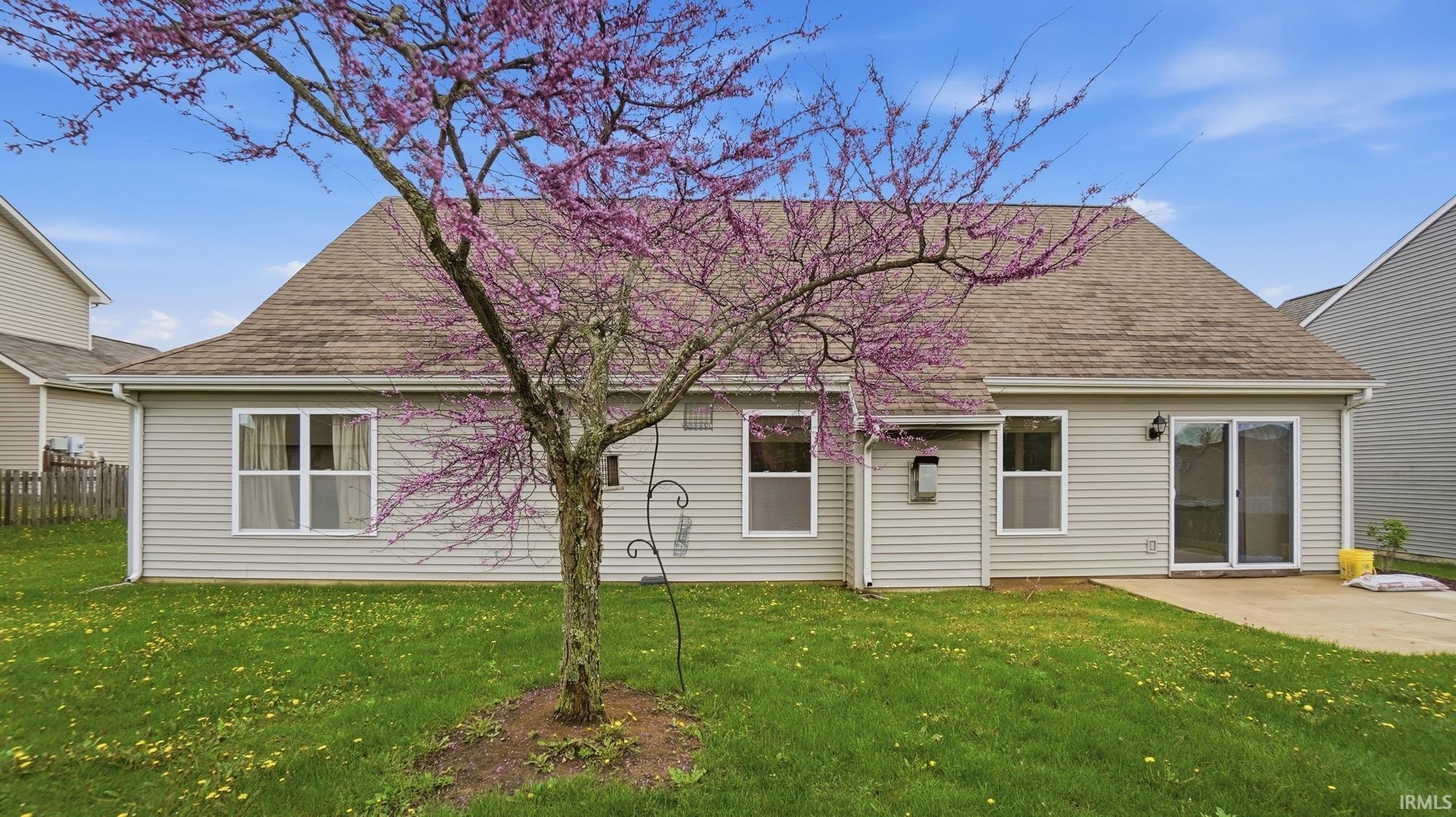 Back of house with a shingled roof and a patio area