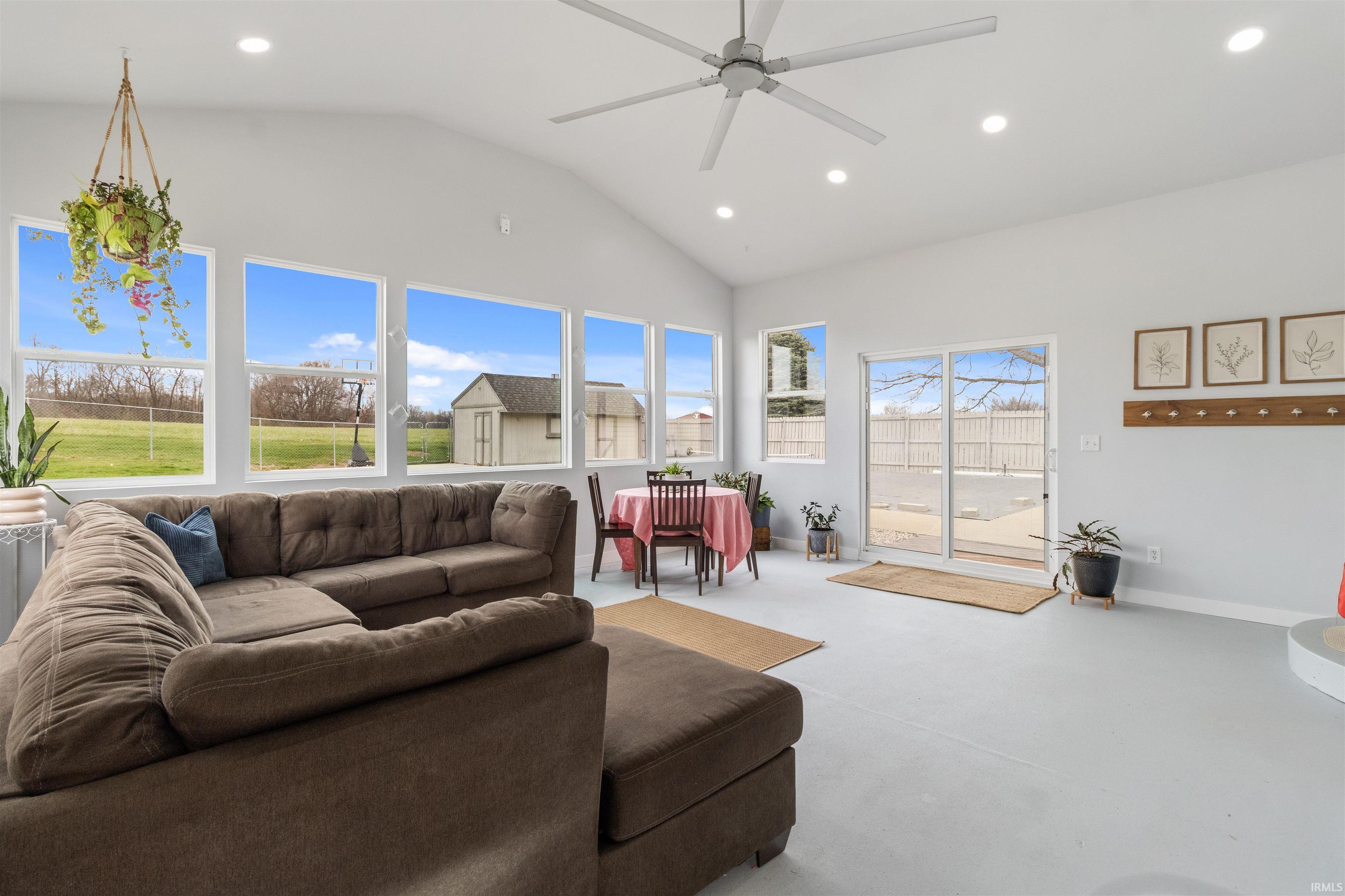Living room featuring recessed lighting, a ceiling fan, vaulted ceiling, and finished concrete flooring