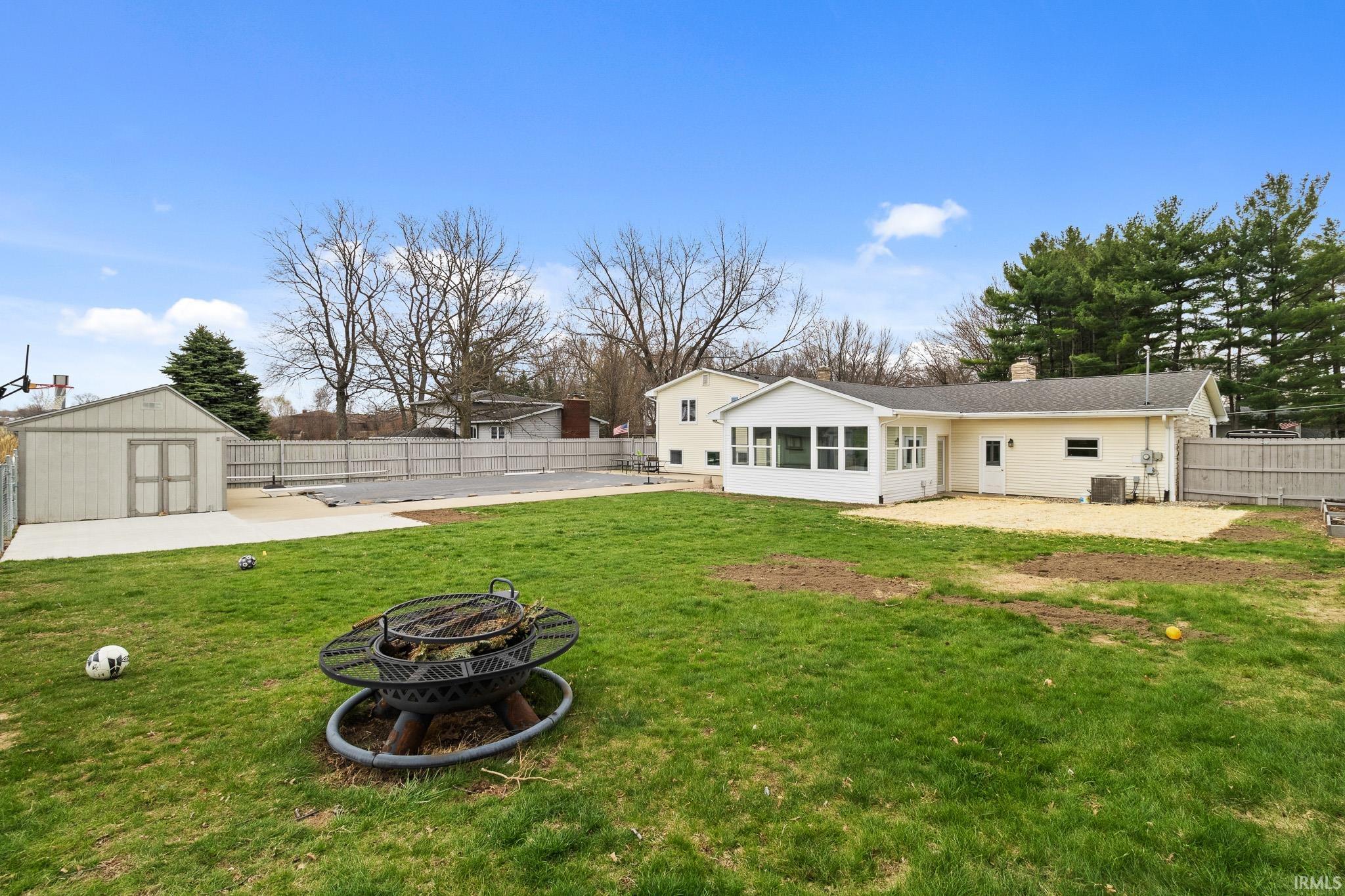 Rear view of property featuring a patio area, a storage unit, a fenced backyard, a chimney, and a sunroom