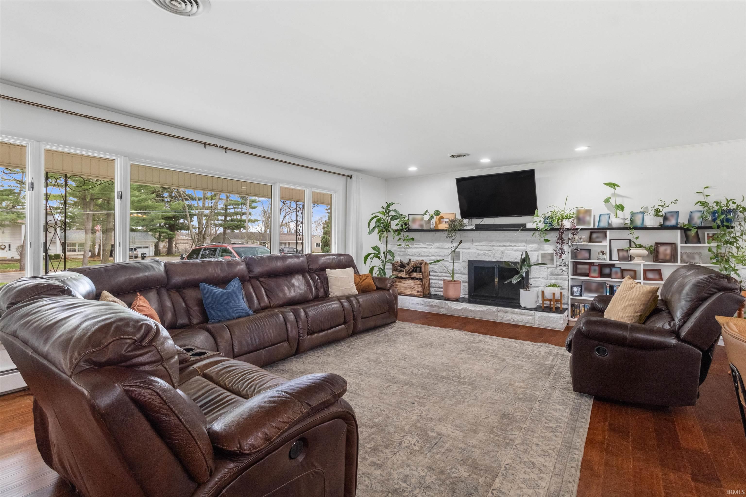 Living area featuring wood-type flooring, a stone fireplace, and recessed lighting