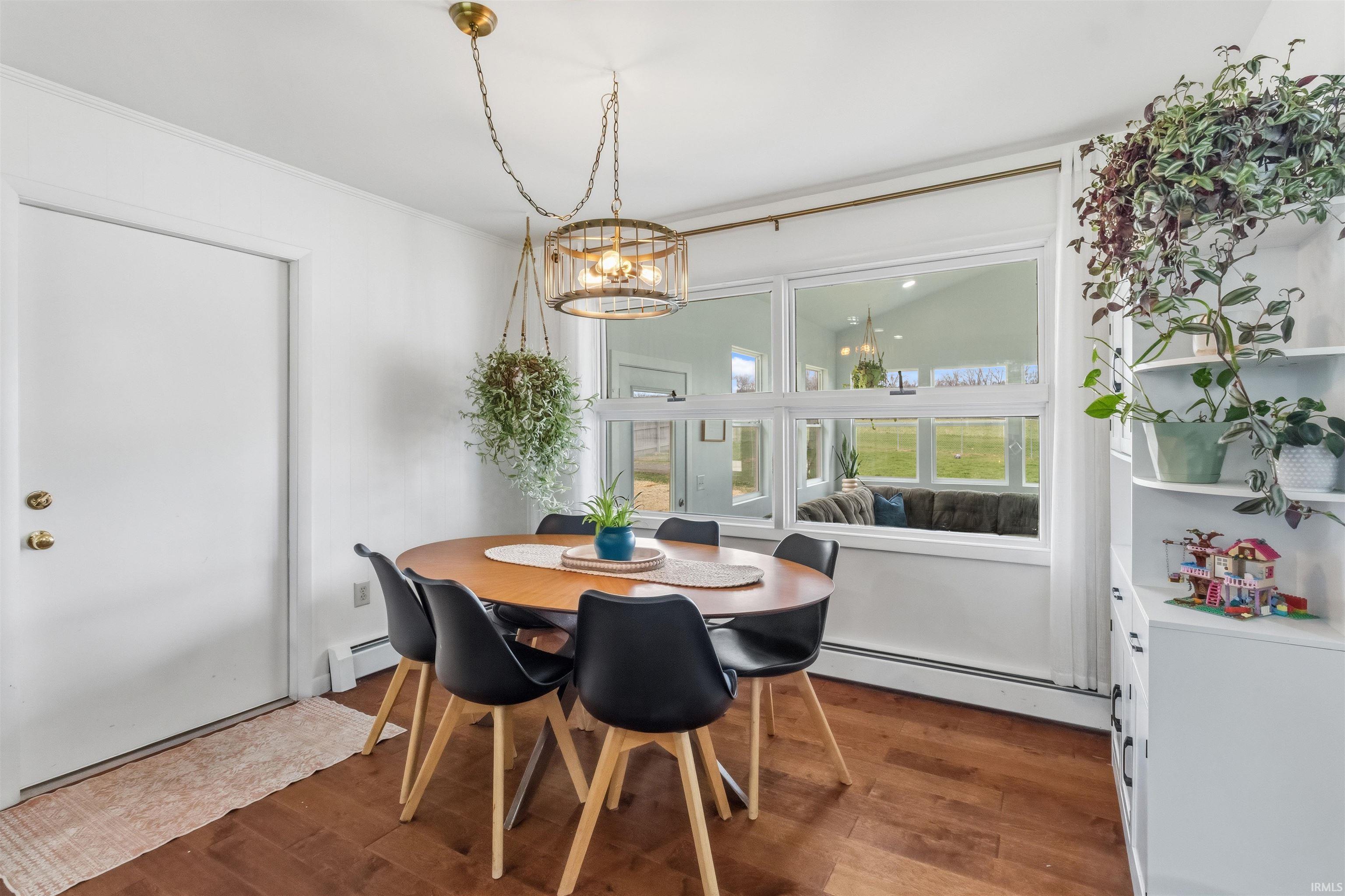 Dining area with a baseboard heating unit, dark wood-type flooring, and suspended lighting