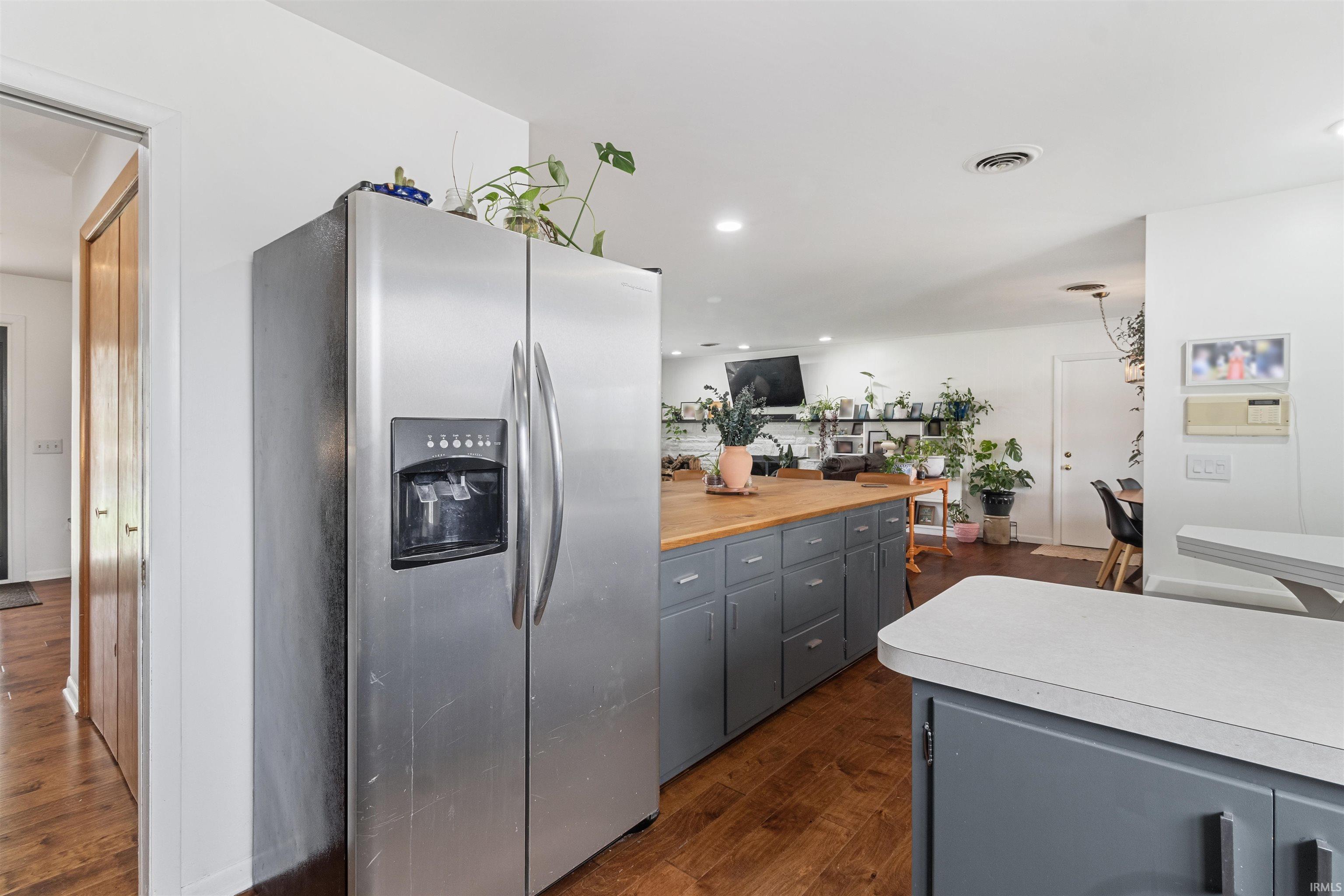 Kitchen featuring stainless steel fridge with ice dispenser, gray cabinets, dark wood-type flooring, and pendant lighting