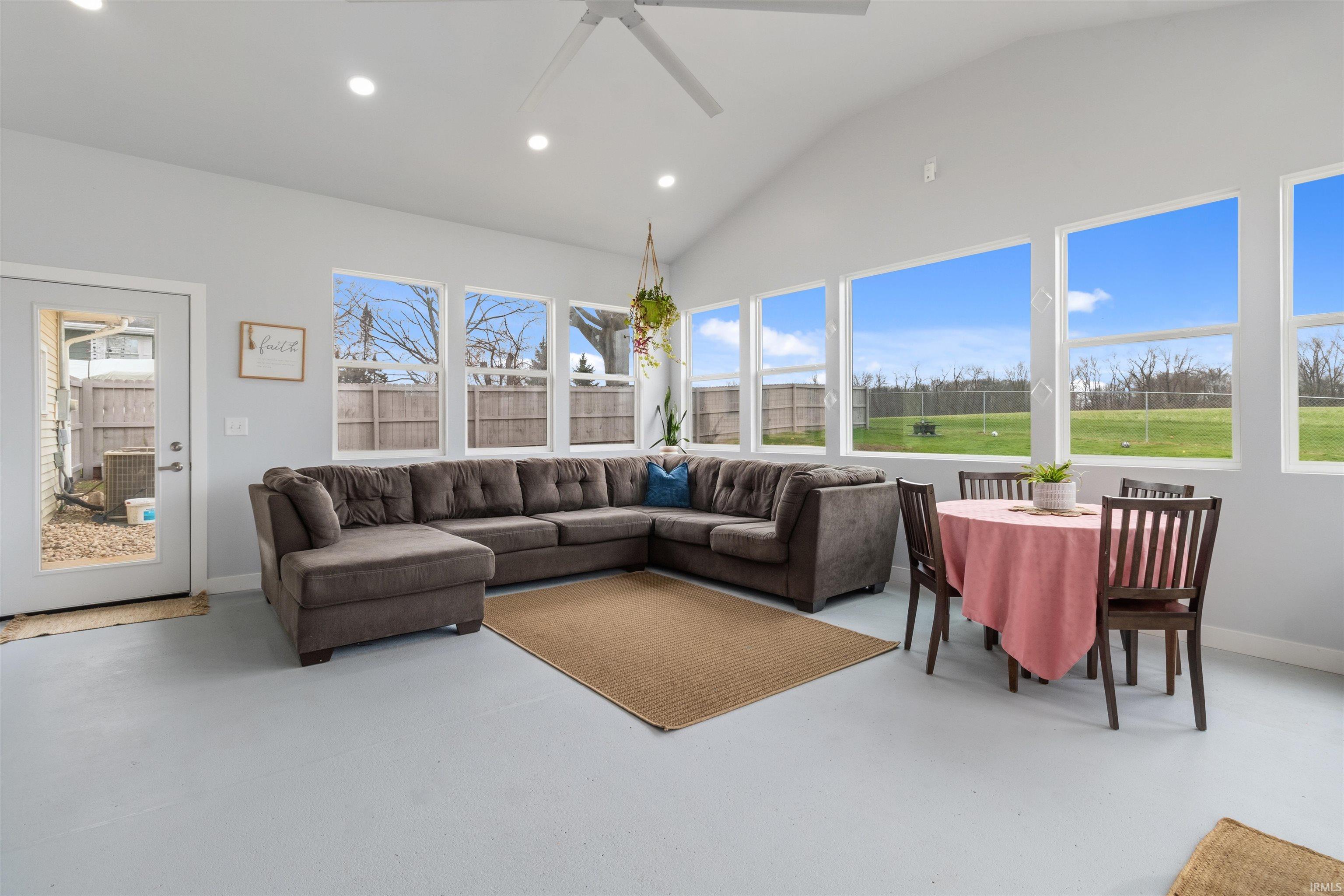 Living area featuring ceiling fan, finished concrete floors, recessed lighting, and vaulted ceiling