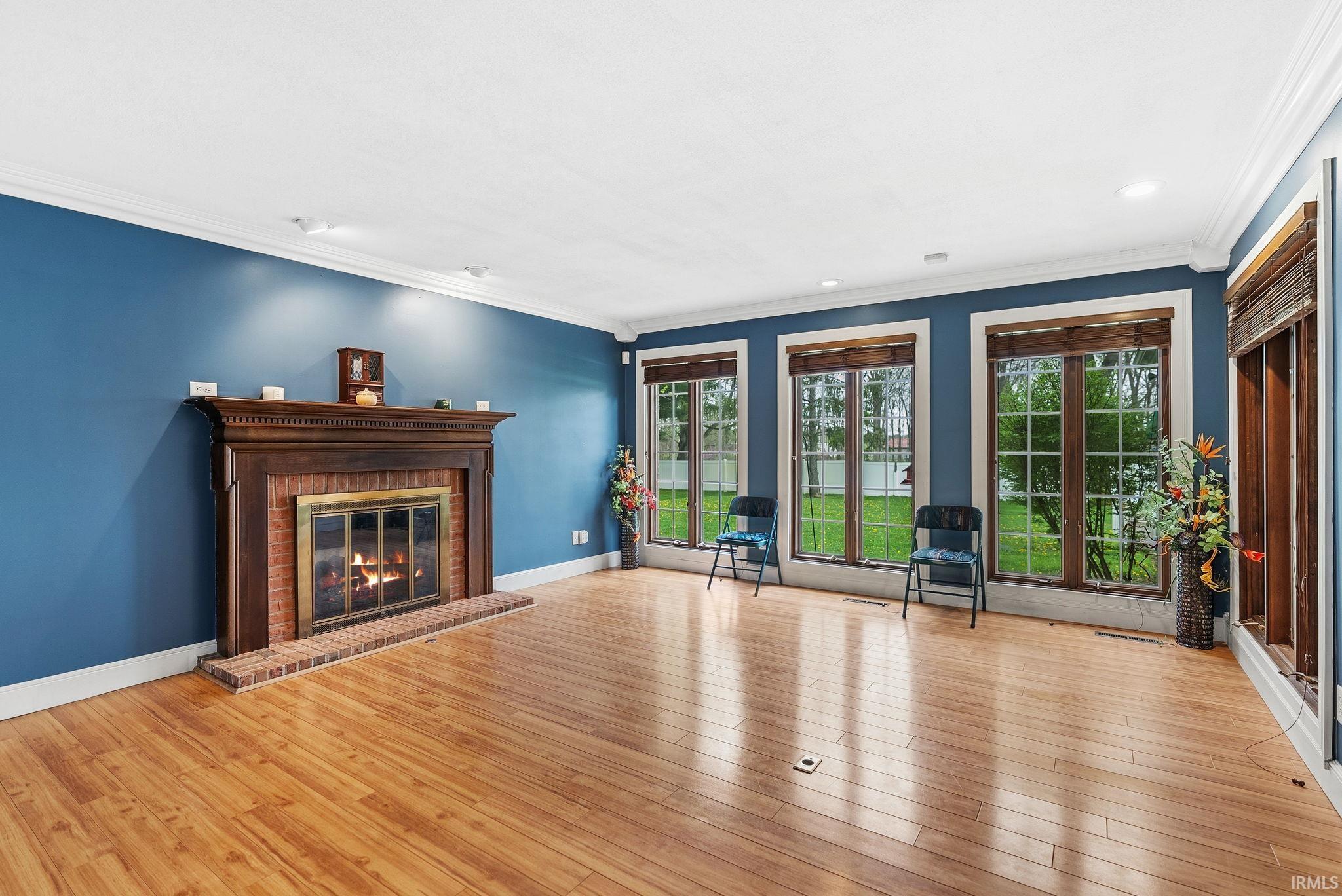 Unfurnished living room featuring ornamental molding, a brick fireplace, light wood-style floors, and recessed lighting