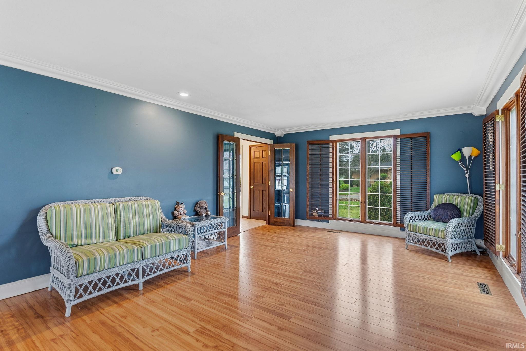 Living area with ornamental molding, light wood-type flooring, and recessed lighting