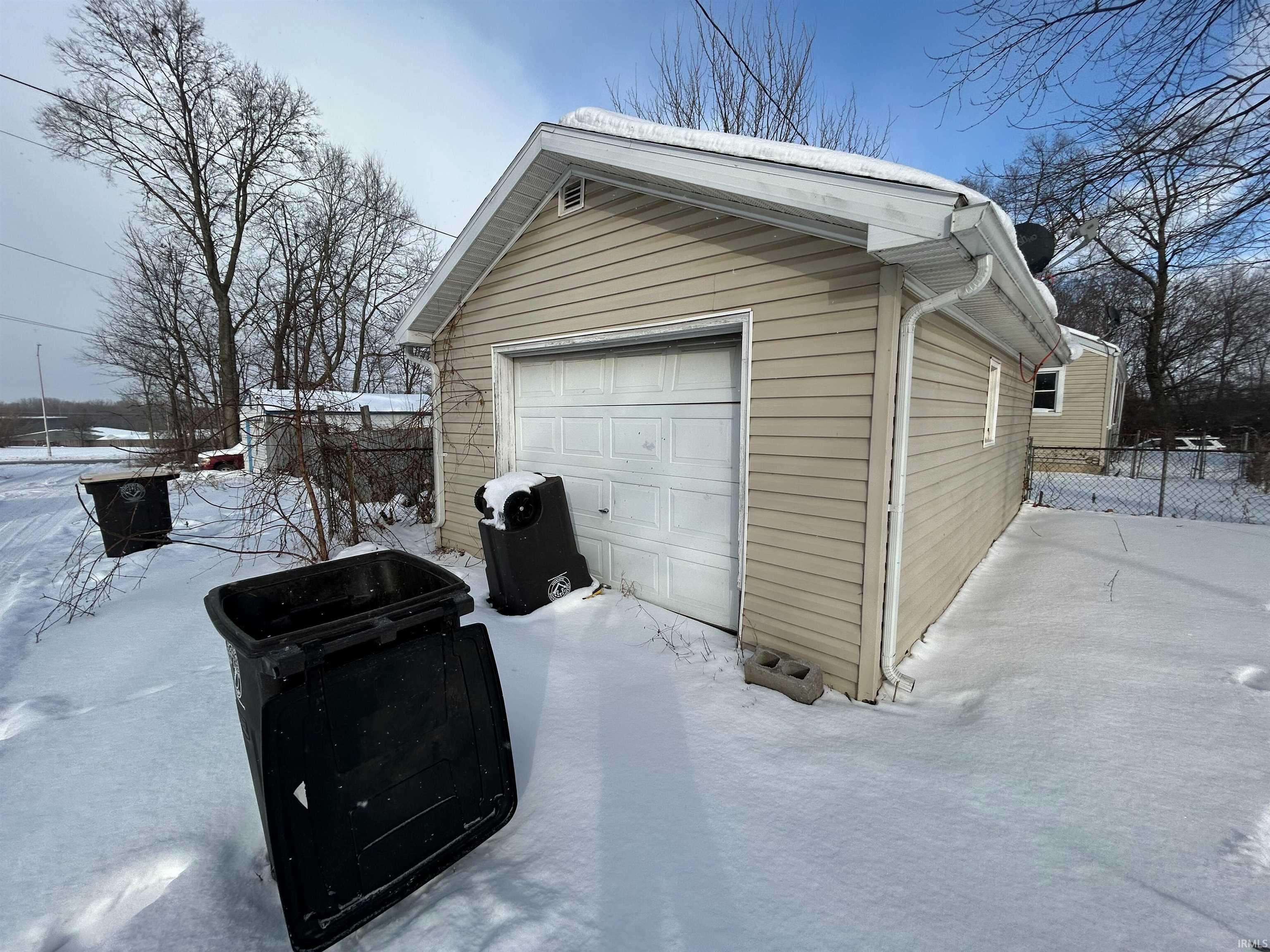 Snow covered garage featuring a detached garage