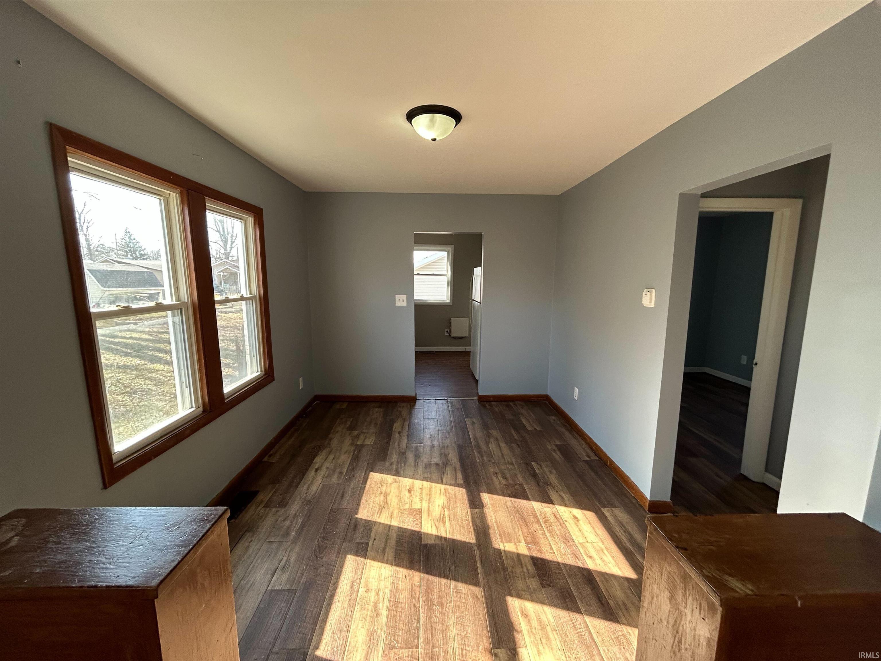 Unfurnished dining area with dark wood-style floors and baseboards