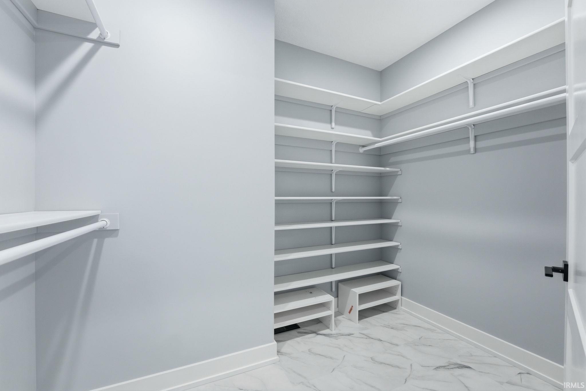 Walk in closet with light marble finish flooring