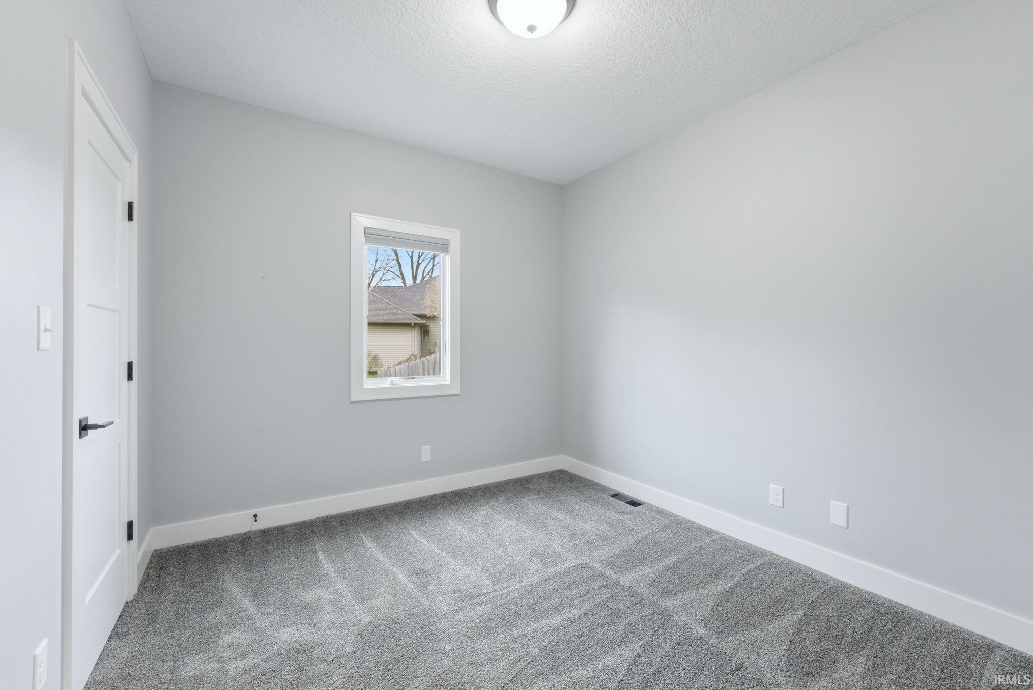Unfurnished room with light colored carpet and a textured ceiling