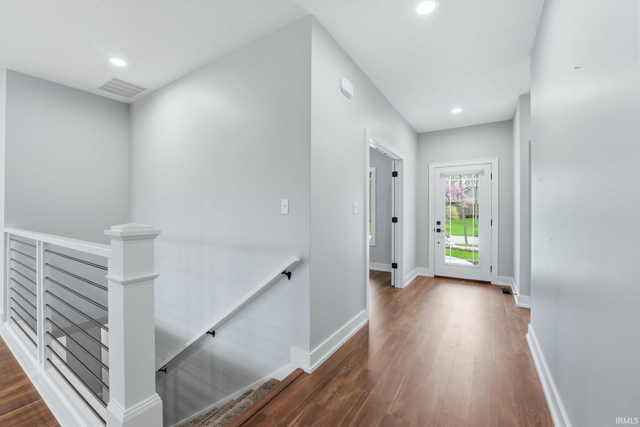 Hall featuring an upstairs landing, dark wood-style floors, and recessed lighting