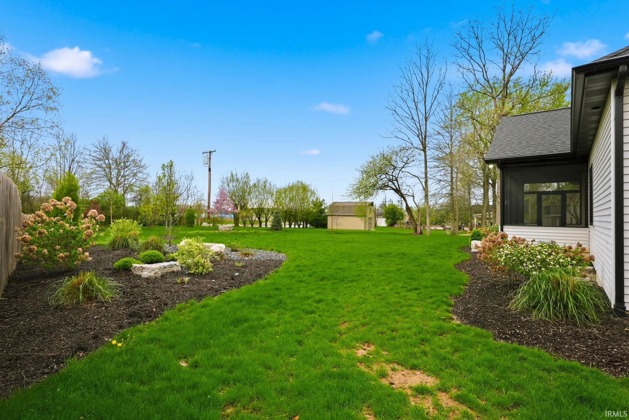 View of grassy yard featuring a sunroom and an outdoor structure