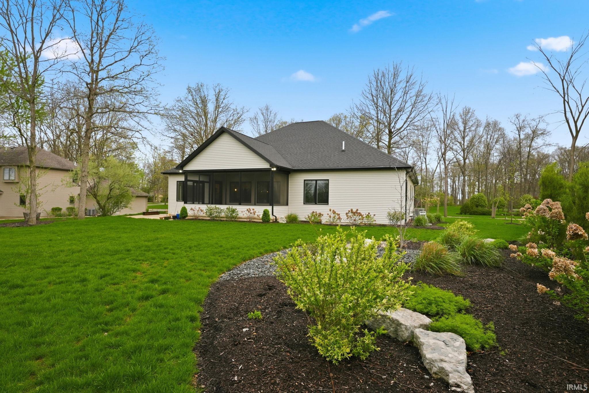 Rear view of property featuring a sunroom, a yard, and a shingled roof