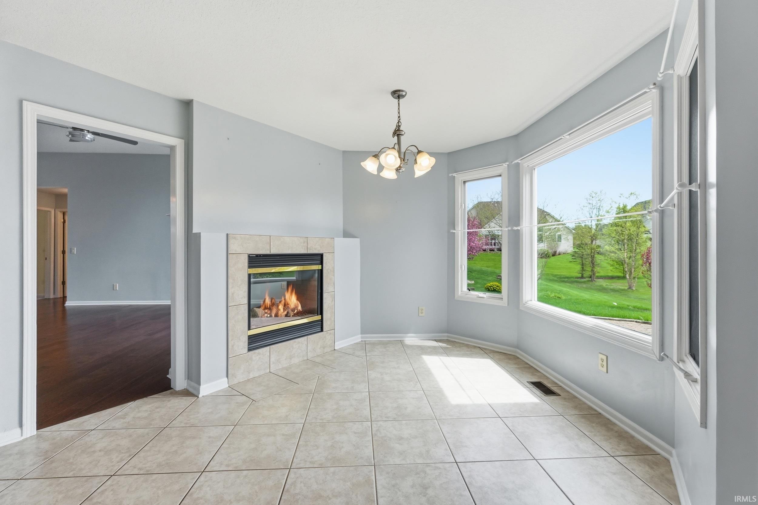 Unfurnished dining area featuring a chandelier, a tiled fireplace, and light tile patterned floors