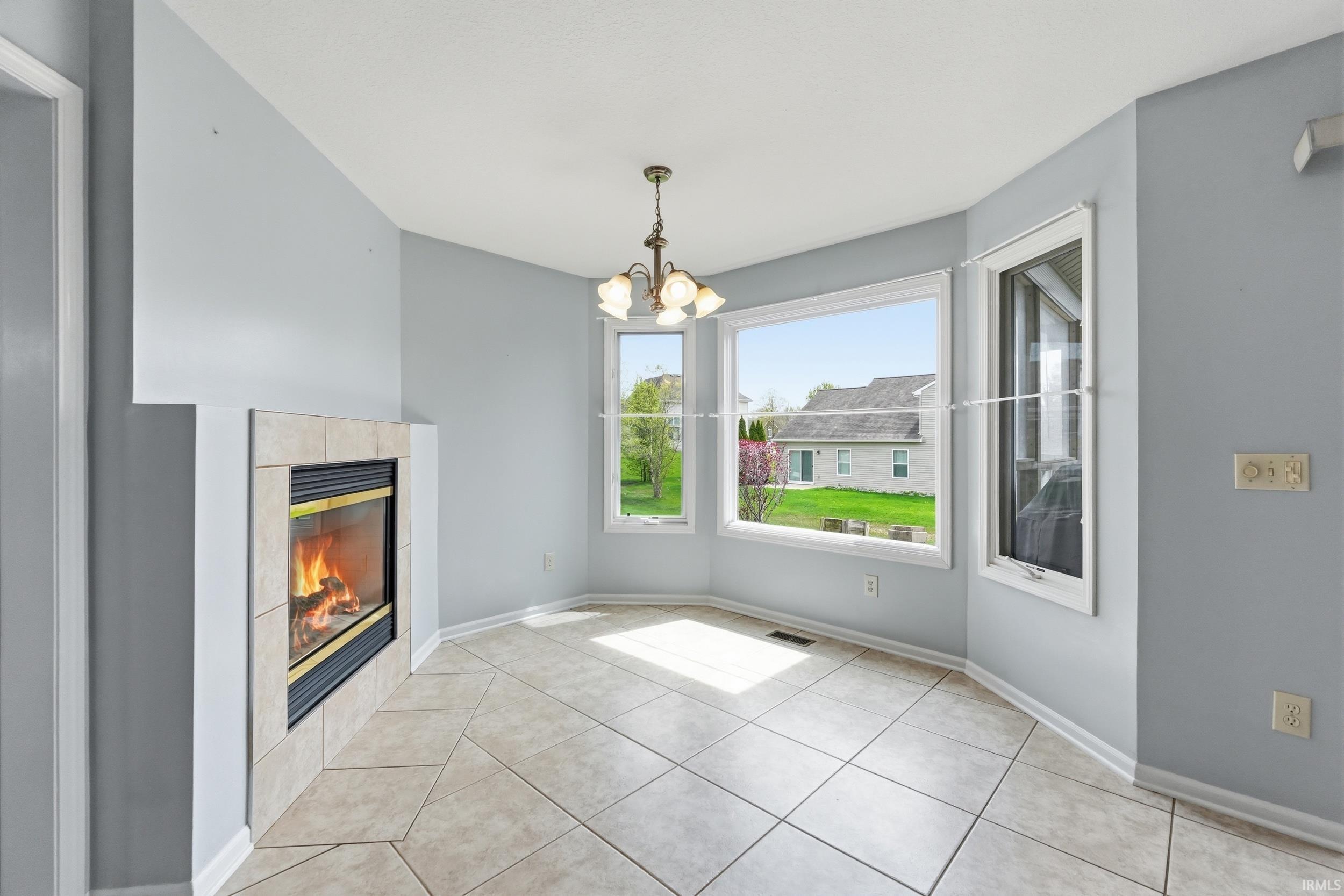 Unfurnished dining area featuring suspended lighting, a tiled fireplace, and light tile patterned floors