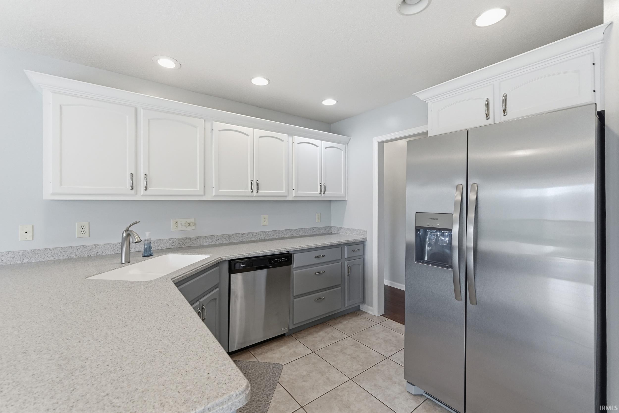 Two tone kitchen featuring stainless steel appliances, dual tone cabinetry, recessed lighting, and light tile patterned floors
