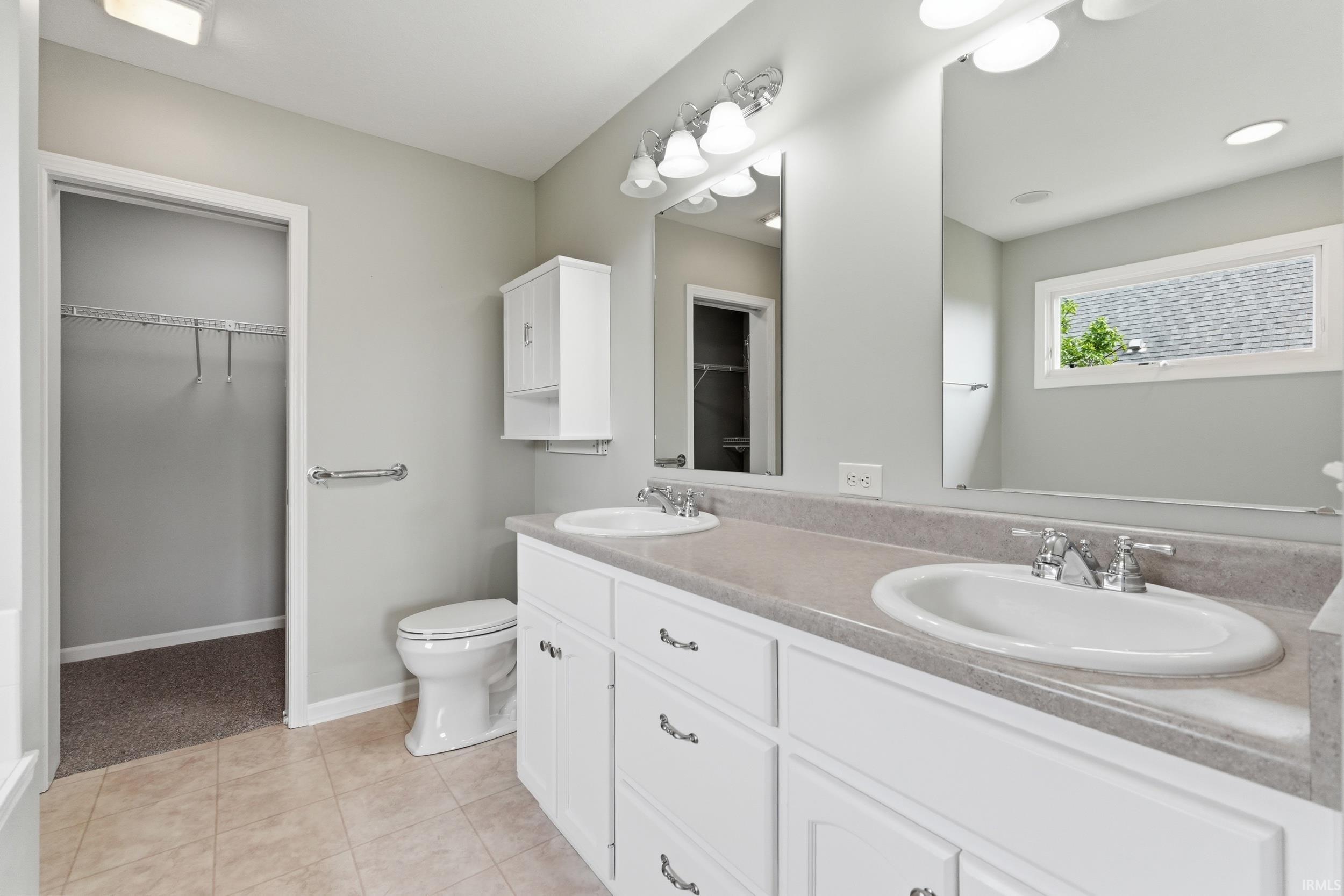 Full bathroom featuring a spacious closet, double vanity, and light tile patterned floors