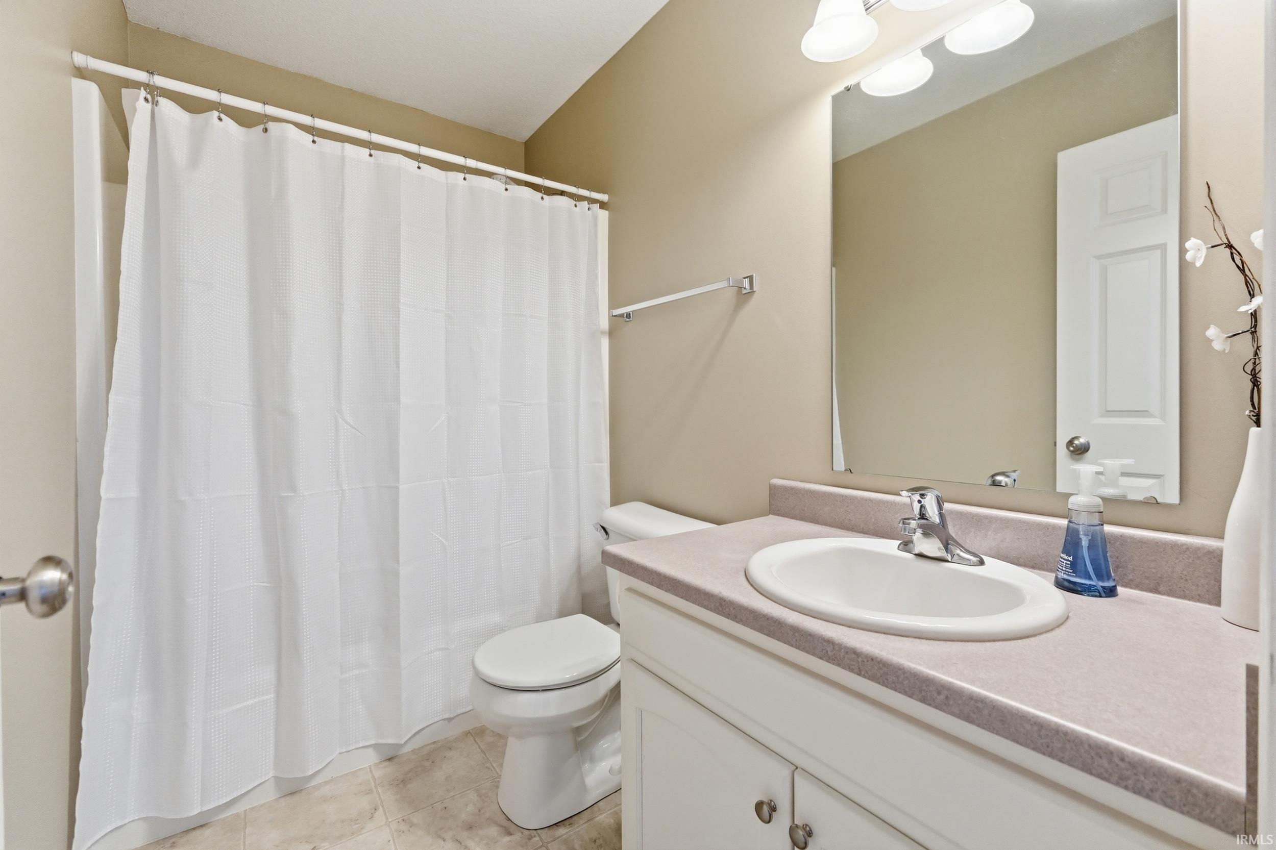 Bathroom featuring vanity, a shower with shower curtain, and light tile patterned flooring