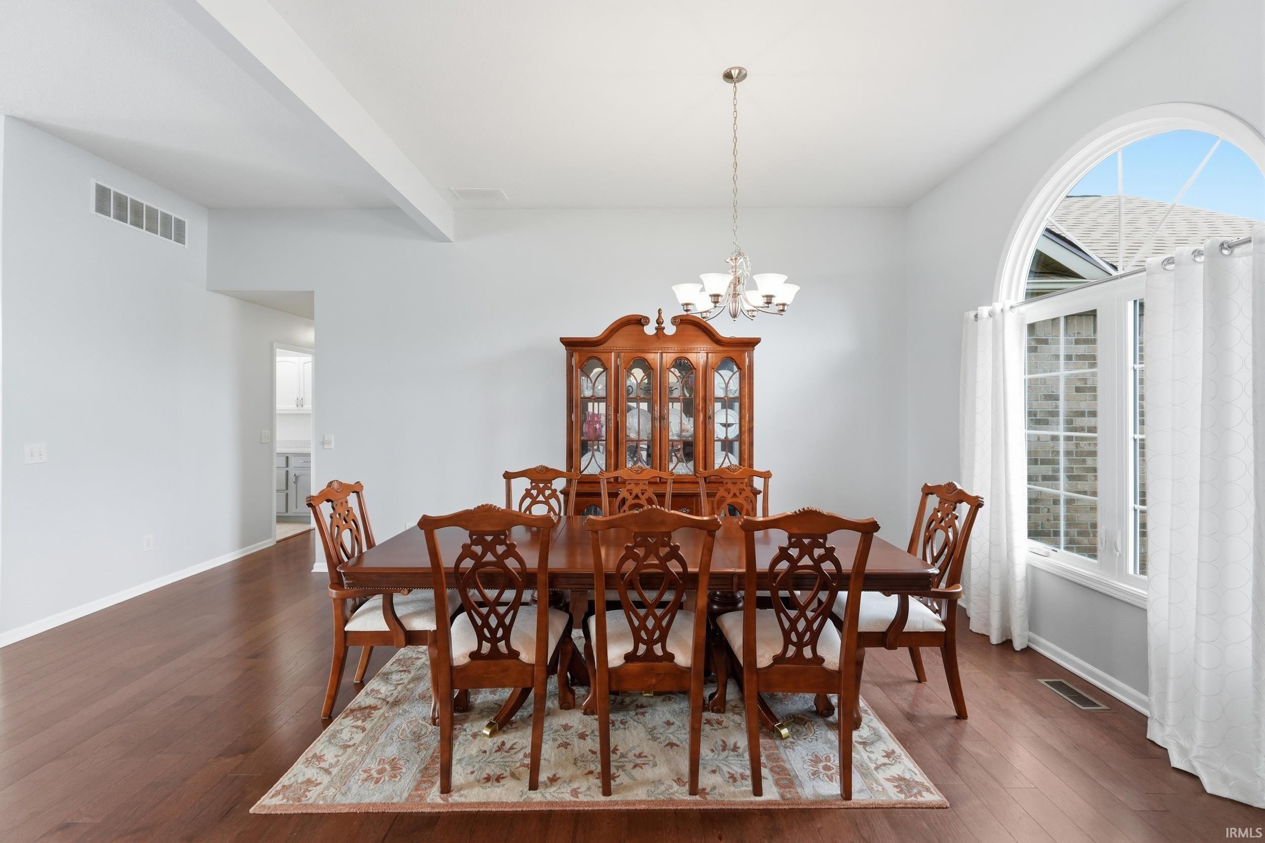 Dining area with dark wood-style flooring, hanging lights, and beam ceiling
