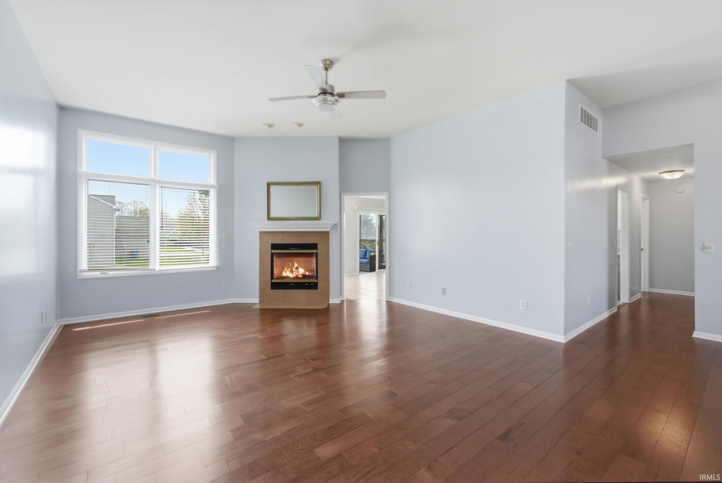 Unfurnished living room with ceiling fan, a fireplace, and dark wood-type flooring