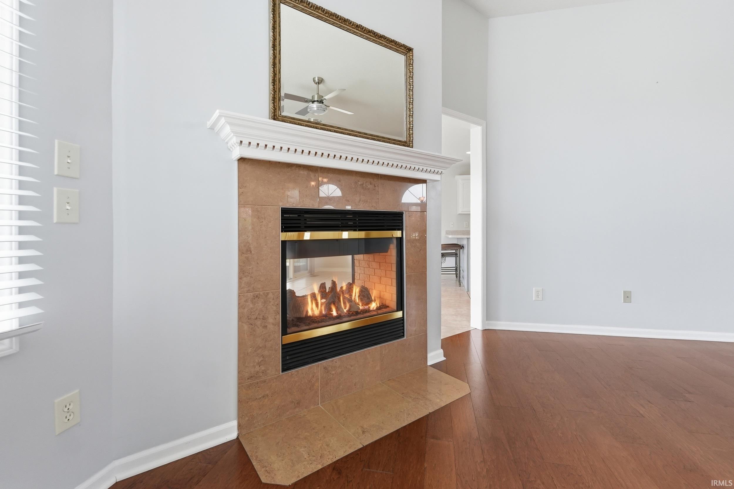 Detailed view of wood finished floors, a tile fireplace, and a ceiling fan